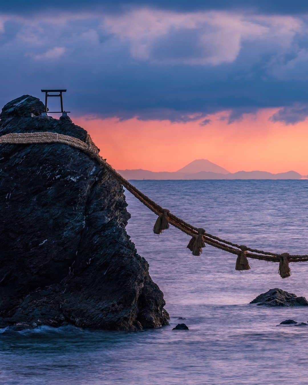 SHOCK EYEさんのインスタグラム写真 - (SHOCK EYEInstagram)「まさかの奇跡！ 伊勢にある夫婦岩からなんと富士山が見えた！！🗻✨  朝日のバックライトに照らされて浮きでた富士山のシルエット。  こんなに遠く離れた富士山が伊勢で拝めるなんて、本当すごいなあ。  富士山を遥拝するために、この夫婦岩があることがこの姿からよーくわかるよね。  しかも地元に住んでいても滅多に見られない光景らしい。 なのに一泊の旅でこの景色に出会えるなんて、、なんてありがたい☺️✨  しかもこの日の海、、 雲の模様、朝日の色がめちゃくちゃ神秘的な色していたよ。  心を込めて手を合わせました🙏✨  #夫婦岩 #伊勢 #二見興玉神社 #富士山 #ise #meotoiwa #mtfuji #fujisan   #japantravel #japantrip #fujifilm #gfx100s #xs10 #beautifuldestinations #discoverjapan #discoverearth #voyaged #awesome_photographers #IamATraveler #wonderful_places #japanphoto #japanphotography #japan_of_insta #livingonearth #theglobewanderer」3月2日 16時24分 - shockeye_official