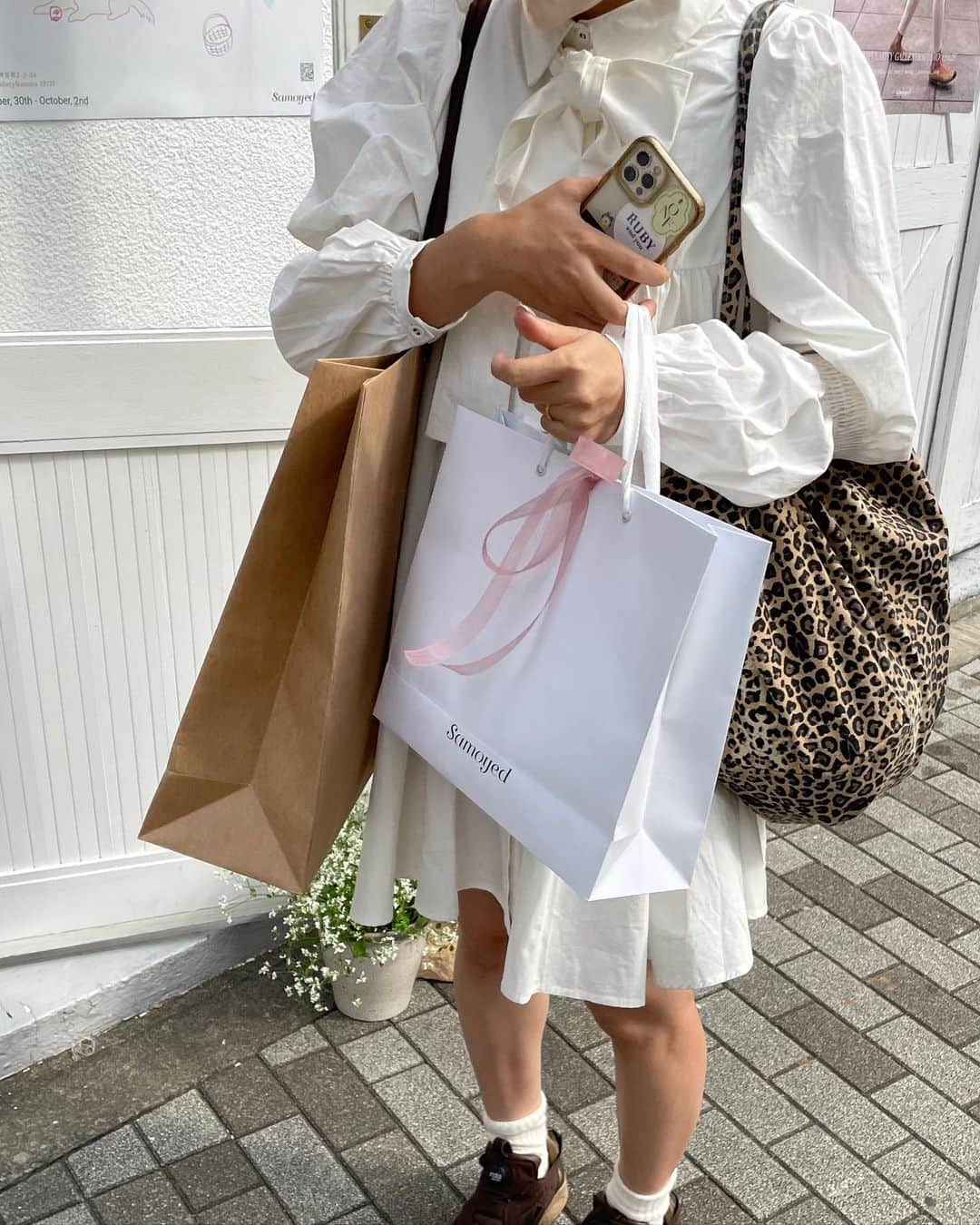 AMOさんのインスタグラム写真 - (AMOInstagram)「爆買い😅 @ samoyed pop up shop. 久々にこんなに大きな紙袋に入れてもらうほどのお洋服をお買い物したかも.. な昨日でした🛍  ちなみにバッグも以前samoyedで購入させてもらったもの🐆🫶🏼  ワンピースは発売したばかりのRUBYの新作です🤍 取り外し可能なボウタイ付き。 ギャザーをたっぷり入れて、ふわっと広がるように... 歩くたびに美しく揺れるように計算した、フレアなシルエット。🦢 袖のデザインもこだわりです✔︎  このワンピース、すでにもう一色のLIGHTBLUEは完売しました👏🏼💙 こちらのOFFWHITEも人気アイテムなので 気になっている方はお早めに..🏹  ⚪️2WAYボウタイフレアワンピース ↪︎OFFWHITE  @ruby_and_you #rubyandyou」9月30日 21時00分 - amo_whale