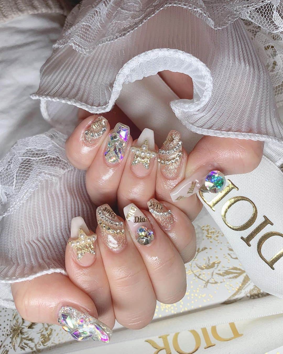 まゆぴちゅーさんのインスタグラム写真 - (まゆぴちゅーInstagram)「鬼かわDiorネイル💅💓  @yudia_totalbeauty さんで 初めてネイル行ってきた！！✨✨  待って？？え？？？  可愛すぎません？？🥲🥲💓💓💓  Diorパーツとキラキラで 最強可愛いネイルになりました🥺🥺💓💓 シャンパンピンクゴールドみたいな キラキラのベースの色もかわいい😭🧡  埋め尽くしも間開けて置いて宝石みたいに💎✨  足のネイルもホワイトパールみたいにして 親指にDiorのパーツ置いたよ🫶🏻✨  ここパーツもシールもブランド系とか たーっくさんあってすごかった🥹❤️❤️  ▶︎ @yudia_totalbeauty   ハンドネイルを担当してくれたのは @nail._azu さん💓  かんわいくしてくれてありがとうございます🙈💋 . . . #newnails #キラキラネイル #diorネイル #diorパーツ #diornails #うめつくしネイル #宝石ネイル #チェーンネイル #Vカット #vカットストーン」2月25日 22時15分 - mayu_03pichu