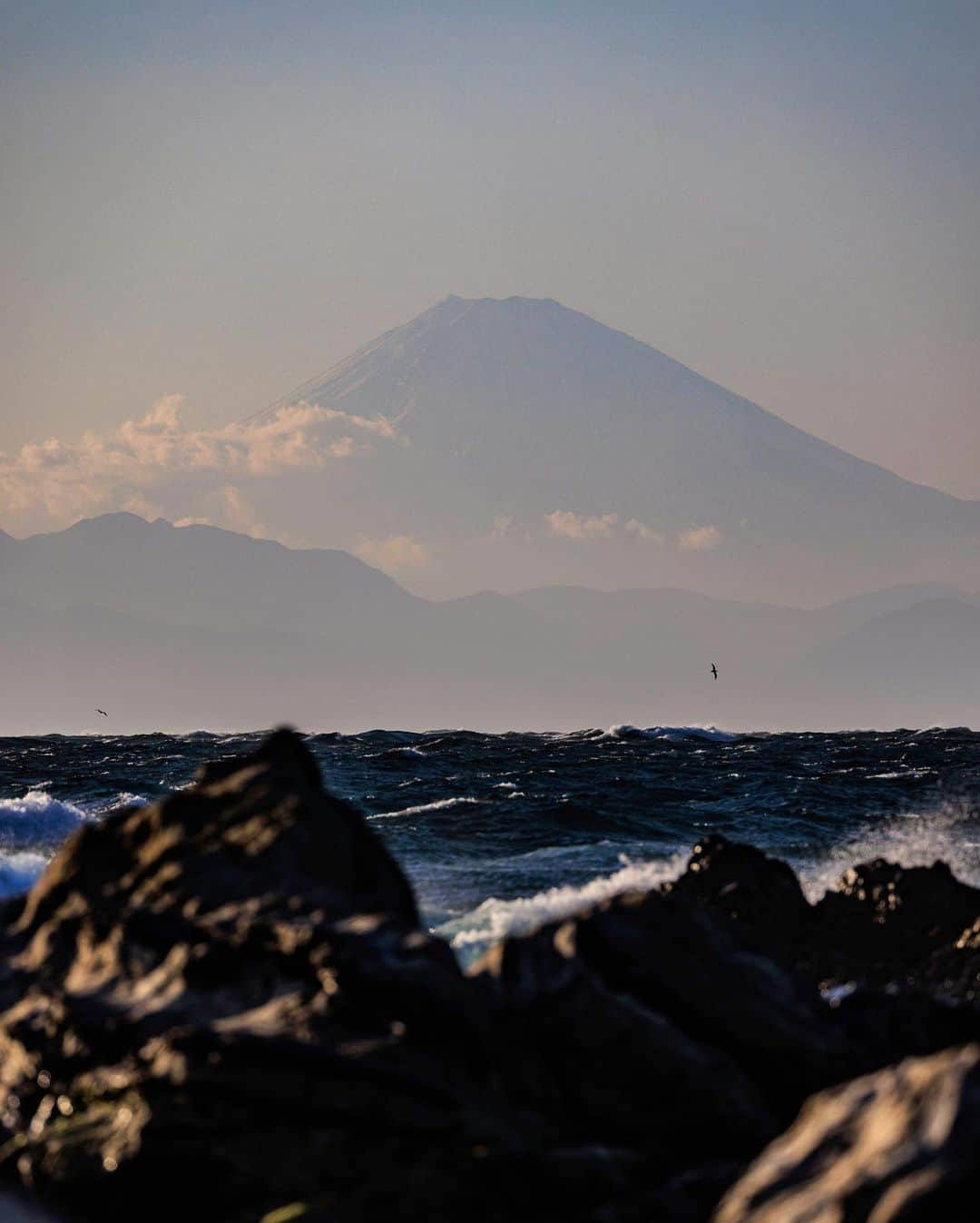 SHOCK EYEさんのインスタグラム写真 - (SHOCK EYEInstagram)「千葉県の館山に富士山を遥拝できる洲崎神社がある。  この存在感。 こんな離れた地でも見ることができるって、それだけ富士山が大きいってことをまじまじと実感させられる。  洲崎神社のこの海辺は僕のお気に入りスポット。 海風に打たれながら、 遠くの富士山を眺める。 この瞬間は全てのことから離れて、美しい景色と対面できる。  往来する船、、どこに行くんだろう？  そんな想いを馳せながら、、手を合わせる。  素敵な毎日に感謝🙏✨  #洲崎神社 #富士山 #館山 #shrine #sunosakishrine #mtfuji #fujisan #fujiyama #japantravel #japantrip #canon #canonR5 #beautifuldestinations #discoverjapan #discoverearth #voyaged #awesome_photographers #IamATraveler #wonderful_places #japanphoto #japanphotography #japan_of_insta #livingonearth #theglobewanderer」3月8日 14時52分 - shockeye_official