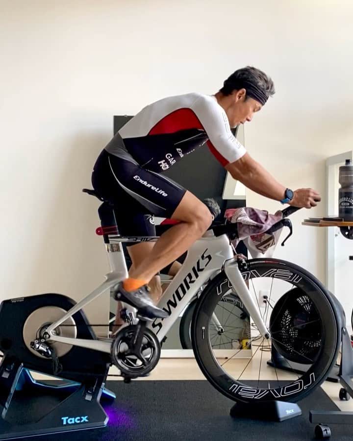 のインスタグラム：「午前中に #インドアサイクリング 1.5時間、今週末の #スペシャライズド #strava #宮古島トライアスロン チャレンジに向けて、時間耐性が徐々あげつつ、#shiv も外乗りしないので装備を外して、鏡から逆の脚も見えるように、アームパッドも最狭にして #shivdisc  にさらに近づける。 インドアだと長時間エアロポジションを取ることはないが、エアロバーを持って体を起こすテクニックは、前乗り過多防止、エアロフォームのリセット、圧迫の分散、骨盤角とペダリング修正に実走でも、瞬間的に取り入れている。 155kmを二日で分けて、100kmと55kmが現実的かな。ランニング42kmはどうしようかな〜 #コナチャレ #anywhereispossible #トライアスロン #garmin #huub #tacx #トレーニング #日日是好日 #エンデュアライフ」