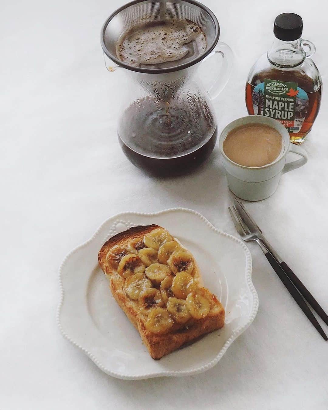 猪鼻ちひろのインスタグラム：「🍞🍌☕️ 朝はパンの気分だったので、メープルシロップとバターでバナナをソテーして、バルミューダで美味しく焼いたパンに乗せました。 東京出身だけど、厚切りのパンが好き。  大好きなひとたちから貰ったコーヒーグッズたちのおかげで、お湯もすぐ沸くし、朝から豆挽けるし、お湯のぽとぽと落ちる音を聞けるし、毎日豆乳ラテ飲むのがたのしみ🥰 (ブラック飲めないんかい！) ということで現場からは以上です。 皆さまの夜ご飯はなーあに？🍚 #テーブルに白い布敷いて気分はカフェよ！ #おうちカフェ #おうち時間 #バナナトースト #トーストアレンジ #ちひろkitchen #ちひろのごはん」
