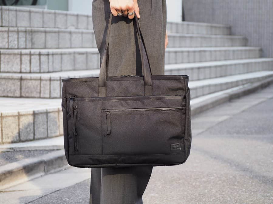 B JIRUSHI YOSHIDAさんのインスタグラム写真 - (B JIRUSHI YOSHIDAInstagram)「【NEW ARRIVAL】 ＜PORTER＞ "PORTER INTERACTIVE TOTE BAG" ・ 軽量で撥水性にも優れ、デイリーユースとしての機能性を充実させた、幅広い年齢層に向けたベーシックなケミカルビジネスシリーズです。 ・ 本体生地は600デニールのポリエステルオックスで、裏面にTPU加工を施した素材を採用しています。TPU（サーモプラスチックポリウレタン）はPVCに比べて軽量で耐久性も高く、環境にも優しいことからアウトドアブランドでも非常に多く採用されている加工です。 ・ ファスナーには軽さと操作性の良さを重視しつつ、見た目は金属ファスナーのように見えるMETALUXE(R) Toughと呼ばれるYKKビスロンの高強度タイプを採用しました。ムシ(エレメント)の樹脂にガラスファイバーを練り込み、通常のビスロンファスナーより165%の高強度化、金属ファスナーより56%の軽量化を実現しています。 ・ 裏地は420デニールのナイロンオックスの表面に、テフロンファブリックプロテクター加工をして堅牢性を高めました。汚れが付着しづらい特性を活かし、グレーカラーを採用してカバンの中身の視認性を高めています。 また、全てのアイテムにPCやタブレットの収納に適したポケットを備え、トロリーバー通し機能も取り付けています。 ・ このトートバッグは、１層式でB4サイズの書類が入ります。 肩にも掛けることができるハンドルの長さで、15inchのPCが収納可能です。 ・ COLOR:BLACK ¥24,000+TAX ・ #bjirushiyoshida #B印YOSHIDA #代官山 #daikanyama#TOKYO#BEAMS#ビームス#yoshidakaban#吉田カバン#ポーター  #porter #비지루시요시다 #도쿄 #다이칸야마 #빔스 #빔즈 #포터 #데일리룩 #interactive」4月6日 18時18分 - bjirushiyoshida