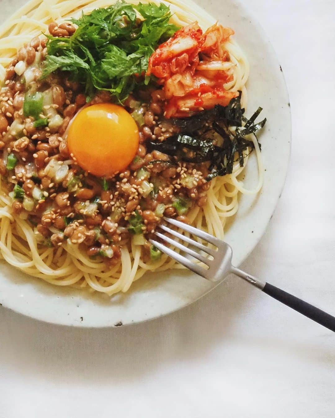 猪鼻ちひろのインスタグラム：「🍝🥚﻿ もぉ〜自炊やる気出ないんですけど〜﻿ けど免疫力は高めておきたいし〜﻿ ってときの乗せるだけパスタ。﻿ ﻿ フライパン使いたくない日の定番。﻿ 刻んだキムチと紫蘇、海苔(写真撮った後に追加した笑)、ネギ、胡麻など好きなもの乗せまして。﻿ 味は胡麻油とだし醤油で🙆🏻‍♀️﻿ 塩昆布ちょっと入れても美味しい〜﻿ あー簡単で美味しいって最高。﻿ ﻿(ブログでもっとちゃんと？詳しく載せてます！) #ちひろのごはん #ちひろkitchen﻿ #納豆パスタ ﻿#納豆アレンジ #手抜きごはん」