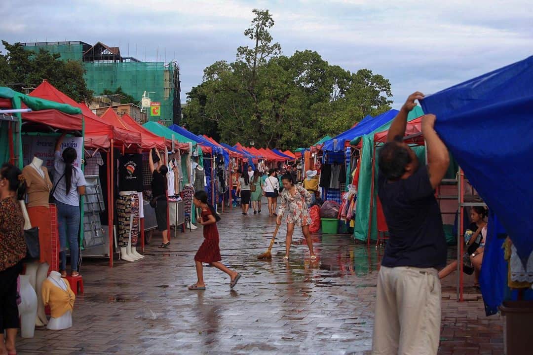 Shunsuke Miyatakeのインスタグラム：「Preparation for Night Market  After the rain. 17:00 in the evening. There are a lot of colorful tents in the riverside park. A person who sweeps a puddle. Children going to peek into the next store. A person who opens a store. Everything from candy to underwear. Still, people gathering in the night market, rather than to buy something, just talk with friends, somehow walk along the river with their family, and move somewhere again.  We can fully spend quality time just by talking to the people you are with, just watching the sunset, or just feeling the breeze blowing along the river. Thinking about that, it might be gauche to think about the purpose or reason whenever we do something.  夜市の準備  雨上がり。夕方17時。リバーサイドの公園に色とりどりのテントがひしめく。水たまりを掃くひと。隣の店を覗きにいくこども。店を開けるひと。駄菓子から下着までなんでも揃う。それでも夜市に集まる人たちは、なにかを買うためというよりは、ただ友達と話しながら、なんとなく家族と川沿いを歩きながら、またどこかへ移っていく。  共に居る人と話しているだけでも、静かに沈む夕陽を眺めているだけでも、川沿いにときおり吹いてくる風にあたるだけでも、十分豊かな時間を過ごすことができる。思えば何かをするのにとにかく目的や理由を考えるのは野暮なことなのかもしれない。」