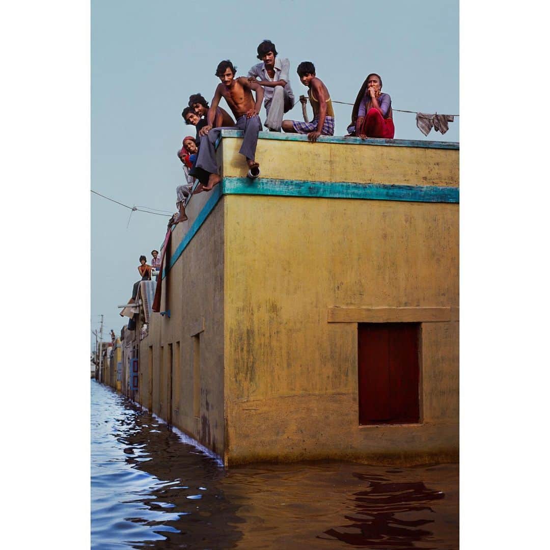 スティーブ・マカリーさんのインスタグラム写真 - (スティーブ・マカリーInstagram)「1st image: Man wades through flooded streets to bring supplies to his family. #Porbandar, #Gujarat, #India, 1983. 2nd image:  People perched on top of a building to avoid the floodwater.」8月8日 0時45分 - stevemccurryofficial