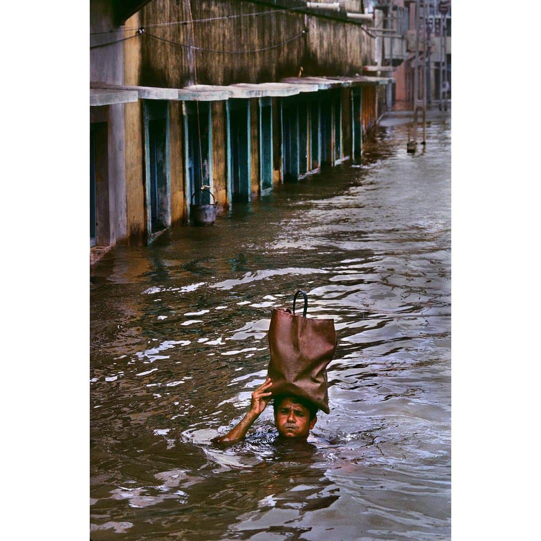 スティーブ・マカリーさんのインスタグラム写真 - (スティーブ・マカリーInstagram)「1st image: Man wades through flooded streets to bring supplies to his family. #Porbandar, #Gujarat, #India, 1983. 2nd image:  People perched on top of a building to avoid the floodwater.」8月8日 0時45分 - stevemccurryofficial