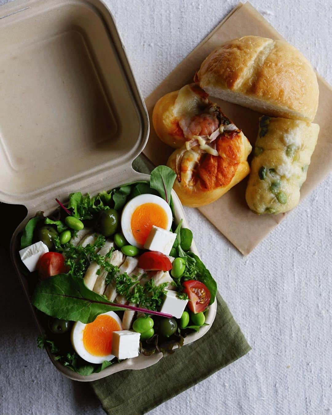 Ryoko Yunokiのインスタグラム：「+ + + Bread and salad bento/パンとサラダのお弁当 . *some bread *Green salad, topped with boiled chicken, baby tomatoes, kiri cheese, hard-boiled egg, edamame and green olives, seasoned with salt/pepper and drizzled olive oil . *パン *グリーンサラダ。茹で鶏、プチトマト、ゆで卵、枝豆、クリームチーズ、グリーンオリーブ。味付けは塩胡椒とオリーブオイル + + #bento #お弁当 #丸の内弁当 #f52grams #紙パック弁当」