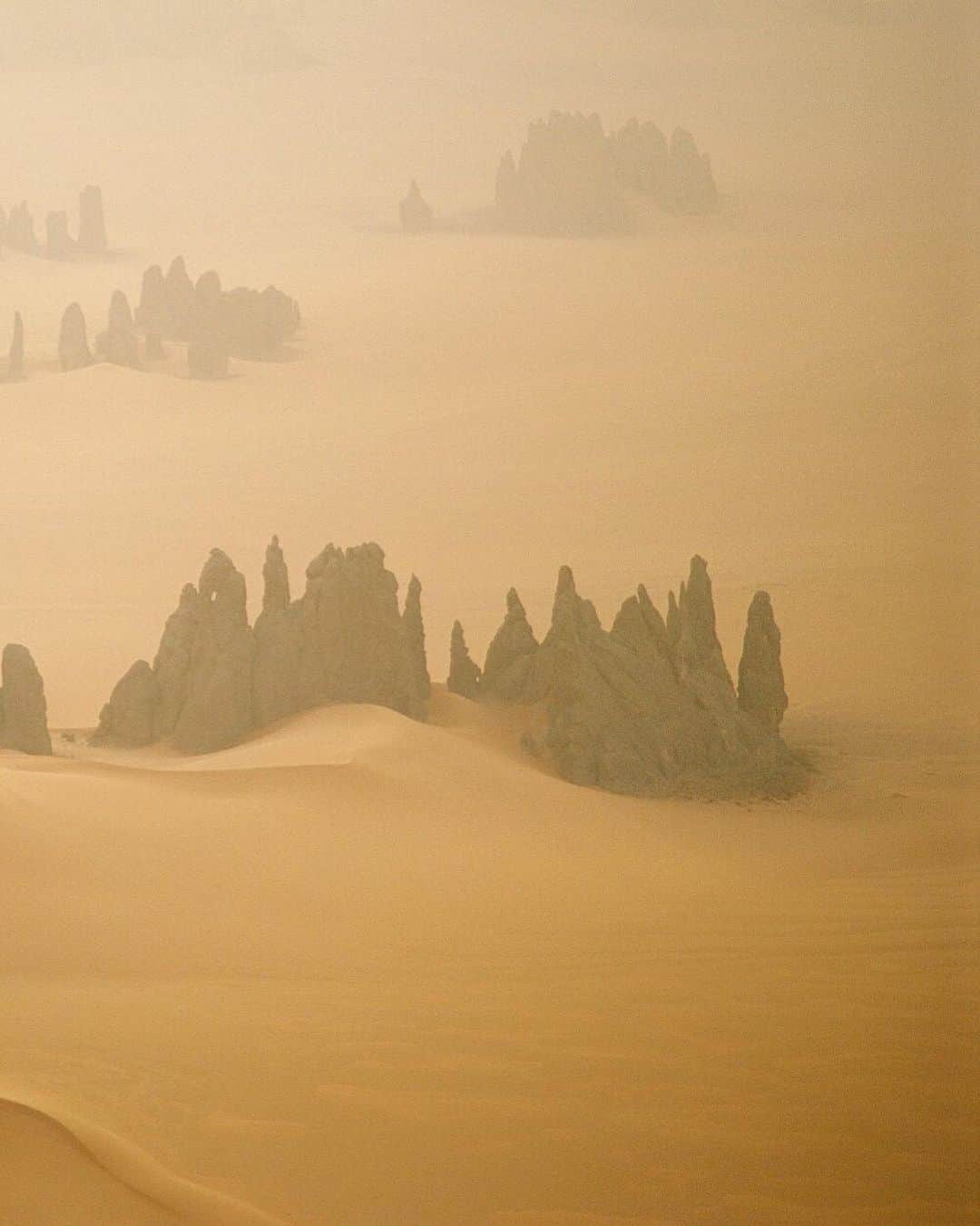 National Geographic Travelさんのインスタグラム写真 - (National Geographic TravelInstagram)「Photo by George Steinmetz @geosteinmetz | Flying in a sandstorm seemed reasonable at the time. We only had a few days up in the far north of Chad before our water ran out, and nobody had ever flown in that surreal forest of pinnacles. #carpediem #paramotor To explore more of our earth from above, follow me,  @geosteinmetz.」8月10日 4時27分 - natgeotravel