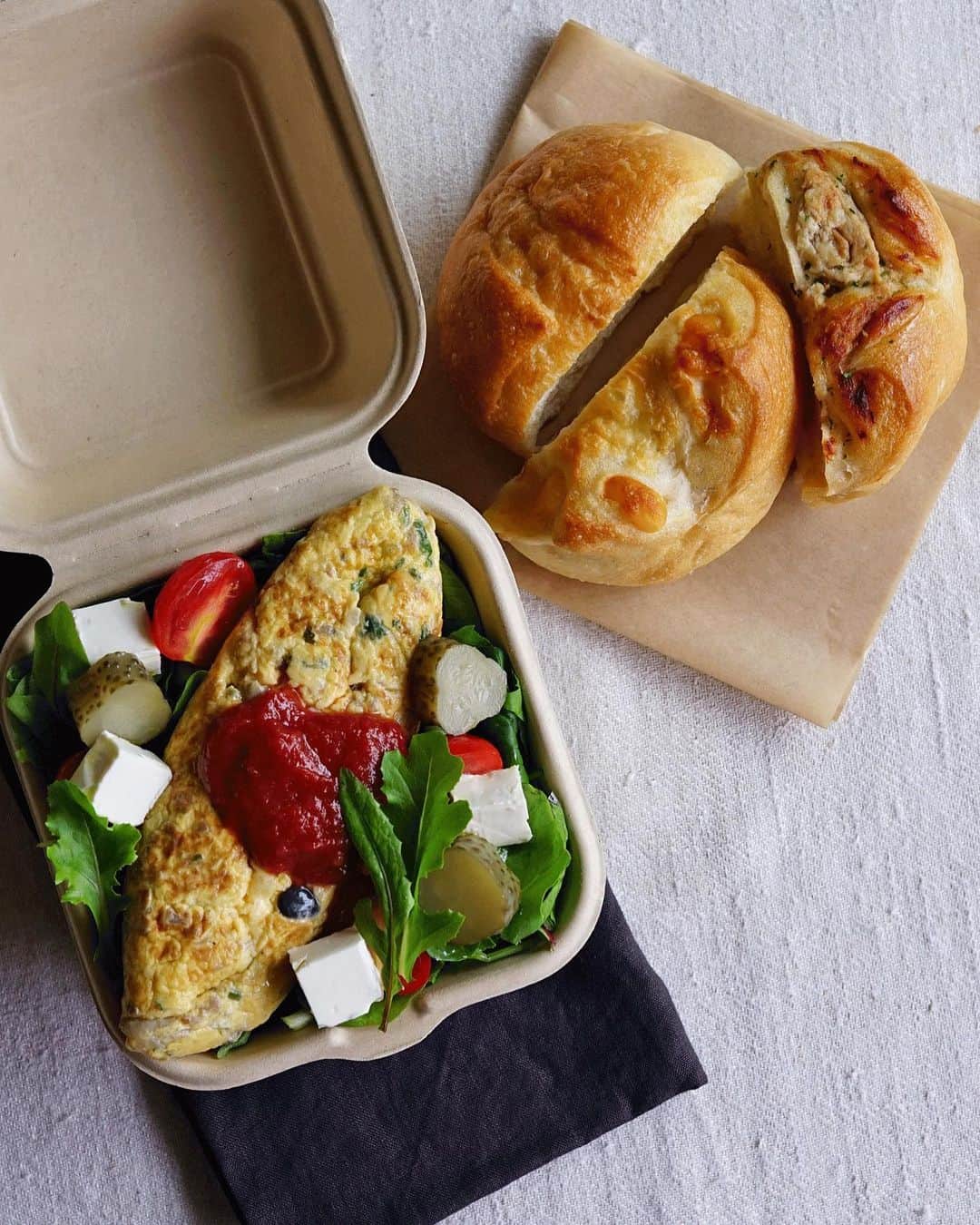 Ryoko Yunokiのインスタグラム：「+ + + Bread and salad bento/パンとサラダのお弁当 . *some bread *Green salad, topped with beef and mushroom omelette, baby tomatoes, kiri cheese, pickles and green olives, seasoned with salt/pepper and drizzled olive oil . *パン *グリーンサラダ。牛ひき肉とキノコのオムレツオムレツ、プチトマト、クリームチーズ、グリーンオリーブ。味付けは塩胡椒とオリーブオイル。 . . beef and mushroom omelette ingredients - eggs, ground beef, mushrooms, chopped parsley and onion, salt and pepper + + + #bento #お弁当 #丸の内弁当 #f52grams #紙パック弁当」