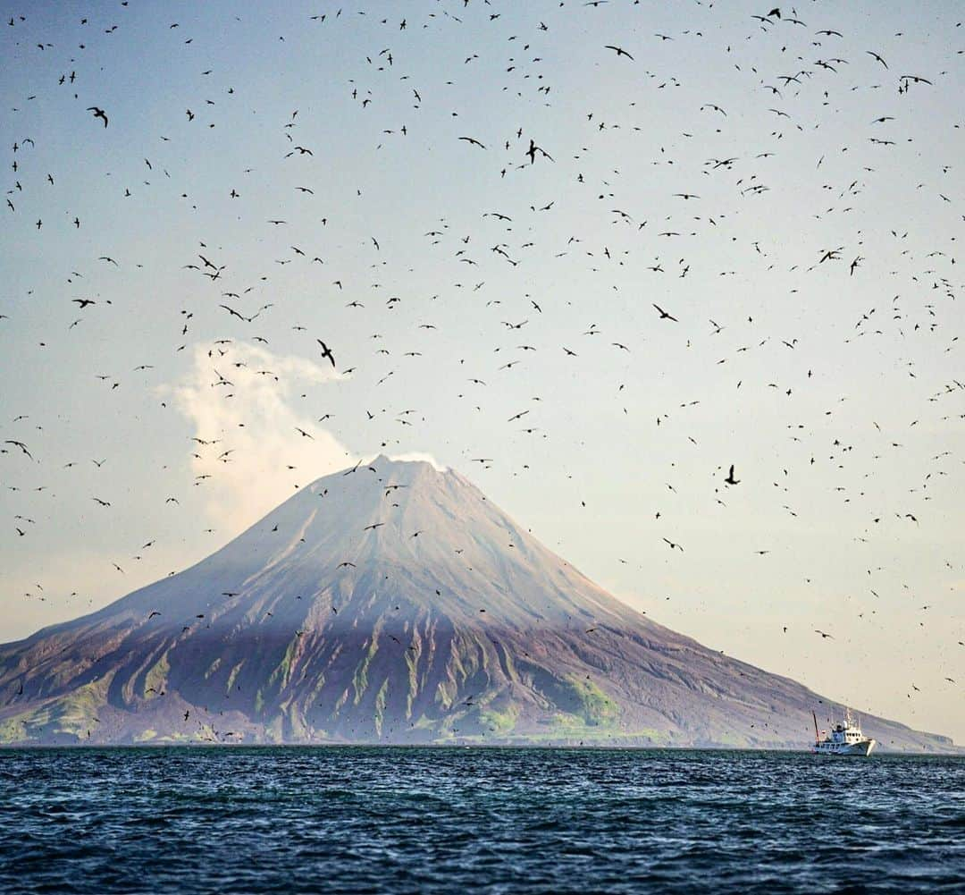 クリス・バーカードさんのインスタグラム写真 - (クリス・バーカードInstagram)「Our boat, The Afina, dwarfed by the scale of active volcanoes & thousands of displaced sea birds carries as many crew as passengers. 24 in total. Sailors, engineers, cook, captain, 1st mate etc etc. all with Russian names we are struggling to pronounce, so often exchange smiles or share coffee we brought to show appreciation. Boats traveling in these rough waters are mandated to carry enough crew in case anything goes wrong. We have been lucky with good weather but their stories & videos of evading storms, waking up to boats covered in ash & weeks of bad weather are horrific. .  #FromKurilsWithLove @taylorfreesolo  @renan_ozturk @jtkerby @tedhesser  @rishisugla  @tomorrow_unlocked  @povel  @_ryanhill_」7月19日 10時49分 - chrisburkard