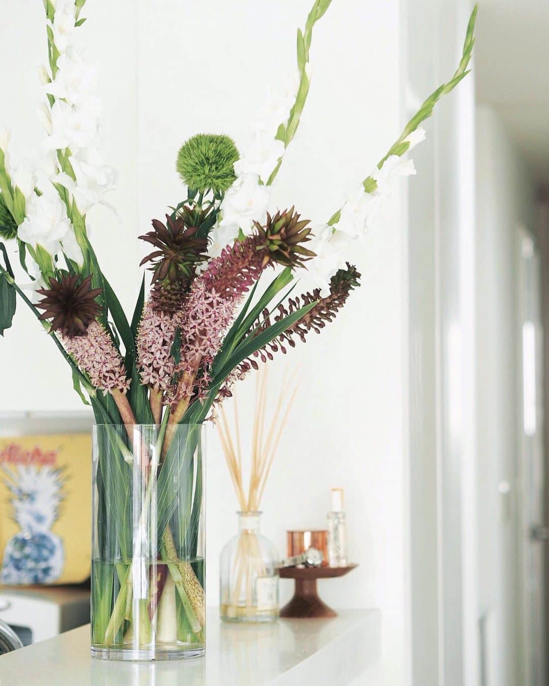 のインスタグラム：「Flowers for the week🏵 . . . . 先にちょこんとパイナップルがついてるみたい🍍😻 小さな星型の花がまた可愛いらしい♡ 南国感がどタイプな今週のお花 . #パイナップルリリー #テマリソウ #グラジオラス . 向こうに見えるパイナップルの絵は Miaがプリスクールで色ぬりしたもの🎨 渋い青が好き💙 . . #今週の花 #flowersfortheweek #flowerstagram #花のある暮らし #夏の花 #naoliving_flowers」