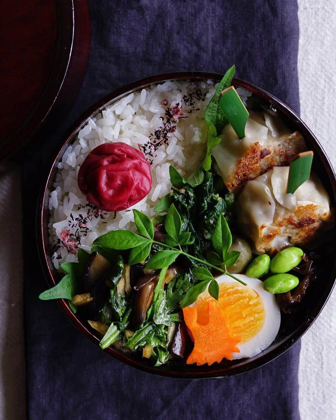 Ryoko Yunokiのインスタグラム：「+ + + Grilled shumai dumpling bento/焼き焼売弁当 . *rice and umeboshi *grilled shumai dumplings *blanched spinach salad with sesame dressing *eggplant and shungiku leaves salad *hard-boiled egg *green olive *edamame *soy-glanzed shiitake mushroom . ＊ご飯と梅干し ＊焼き焼売 ＊法蓮草の胡麻和え ＊茄子と春菊のサラダ ＊ゆで卵 ＊グリーンオリーブ ＊枝豆 ＊椎茸の佃煮 . . Eggplant and shungiku leaves salad ingredients: *eggplant, stir-fried with oil in the pan *shungiku leaves, cut into bite-sized *onion, chopped *dashi-flavored soy sauce + + + #bento #お弁当 #丸の内弁当 #f52grams #曲げわっぱ #井川メンパ」