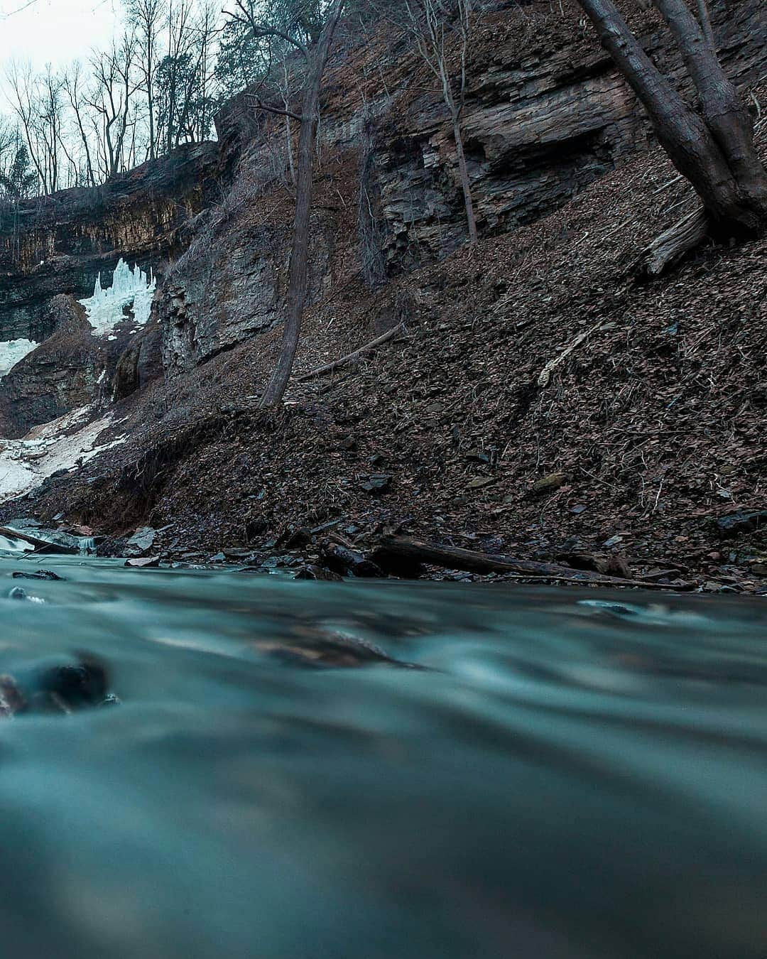 instagoodさんのインスタグラム写真 - (instagoodInstagram)「@fossfocus ❄Cold Vibes❄ === It was just past 7 and the light was going down faster than we had originally anticipated. After hiking around the many other waterfalls Hamilton, Ontario had to offer we found ourselves at the last scheduled waterfall for the day. We were way off the regular path as none of us were willing to settle for the dull, one angle view provided by the small viewing platform near the top of the falls. We had to be right in the middle of the action, and so we made our descent. The path had clearly been used by a select few others with the same idea in mind, yet it was anything but clear cut. Our boots were caked in enough mud to make every uneasy step feel as though the ground would slip out from underneath us at a moments notice. After clambering down rocks with heavy bags swaying around on our backs, testing how good we all believed our balance to be, we found ourselves staring at the final drop. To our left were a set of fringed ropes left by another curious group and to our right, a 70° slope leading down to the base of the 135 ft waterfall. After some talk on the strength and reliability of the ropes we each swung ourselves over the edge and one by one, made our descent. Our hands were red from gripping the rope, trusting it with far more than we should have. As we all splashed down at the bottom of the river and looked up at the final streaks of light shining on the falls, all any of us could do was smile. Standing in the river, I don’t think I had ever been happier to have my feet soaking wet than I did then. I ran further upstream and set my camera tripod right into the flow of water barreling towards us. This is what we saw.」7月24日 23時45分 - instagood