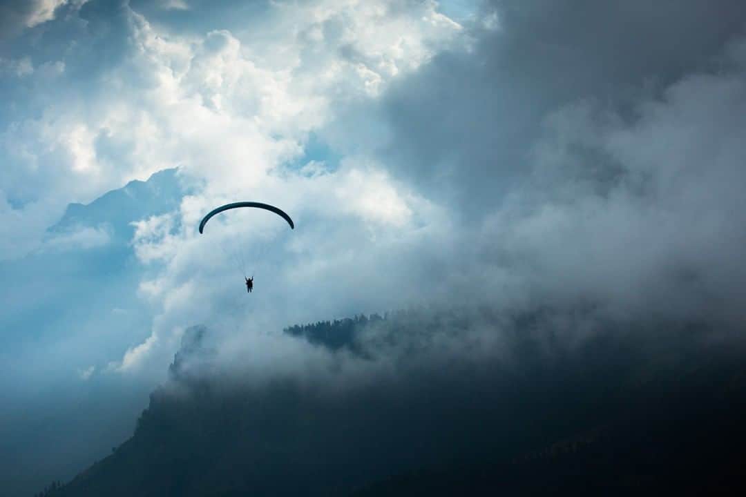 National Geographic Travelさんのインスタグラム写真 - (National Geographic TravelInstagram)「Photo by @emilypolar | A tandem paraglider floats through the clouds above ridges rising from the valley floor of the Kullu district in Himachal Pradesh, India. To see more of India and it's adventures follow me @emilypolar #India #HimachalPradesh #paragliding」8月11日 7時04分 - natgeotravel