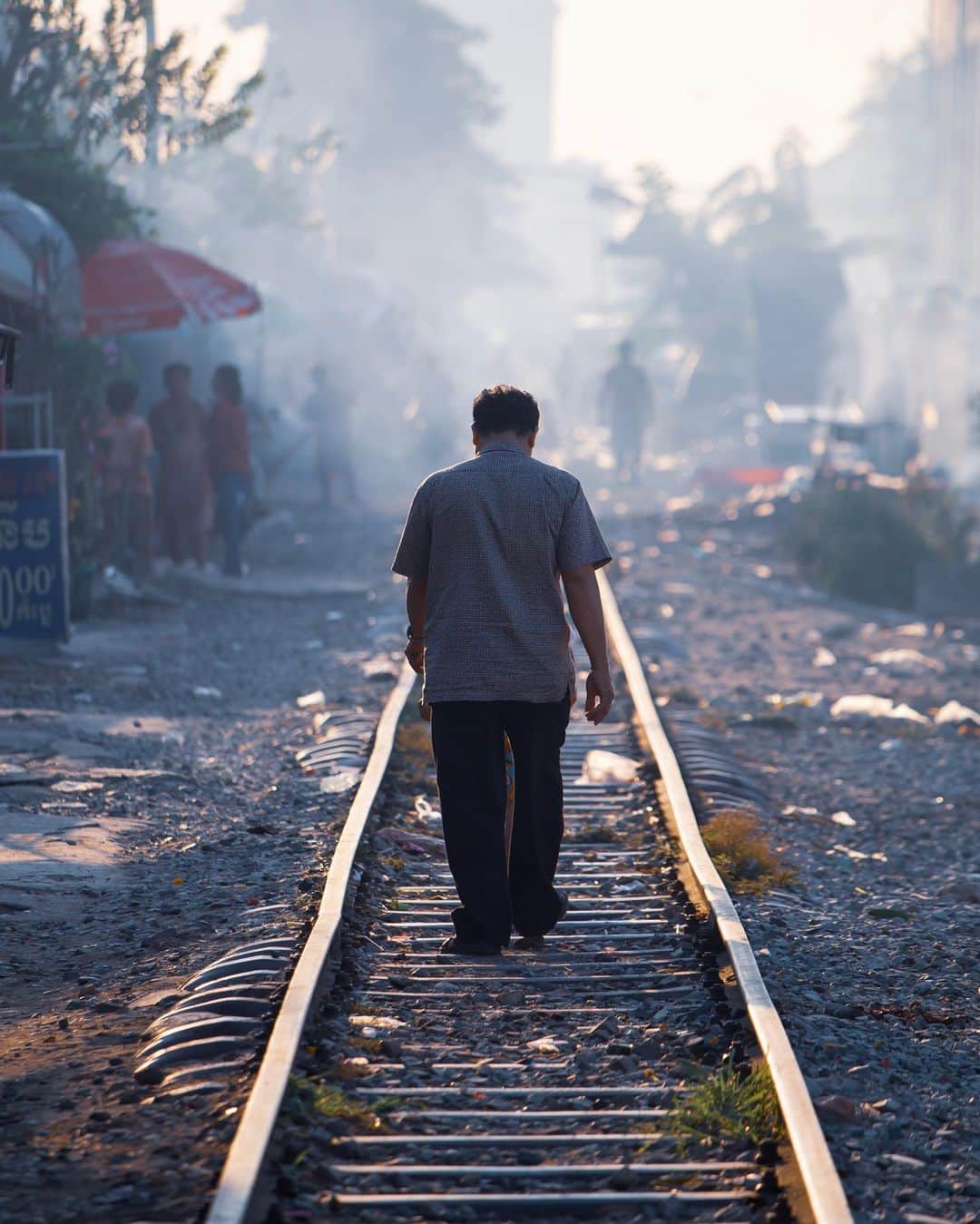 Shunsuke Miyatakeのインスタグラム：「A man walking on the railway with his son / 息子とともに線路を歩く男。  There is a Railway on which we can walk throuhgh in Phnom Penh. I went there with @markus.vdm from 🇿🇦 and @bjoernteufel from 🇩🇪. Some were washing the dishes, some were washing their body with rainwater. Full of smoke from burning something. Full of garbages here and there. In a word, that area is simply shitty. But we saw a Raw Life along the Railway and it was at least fresh experience. No posed, no staged. I will keep on trying to see the world  as it is and trying to find a beautiful story even in a struggling life. How to see the world, that matters.」
