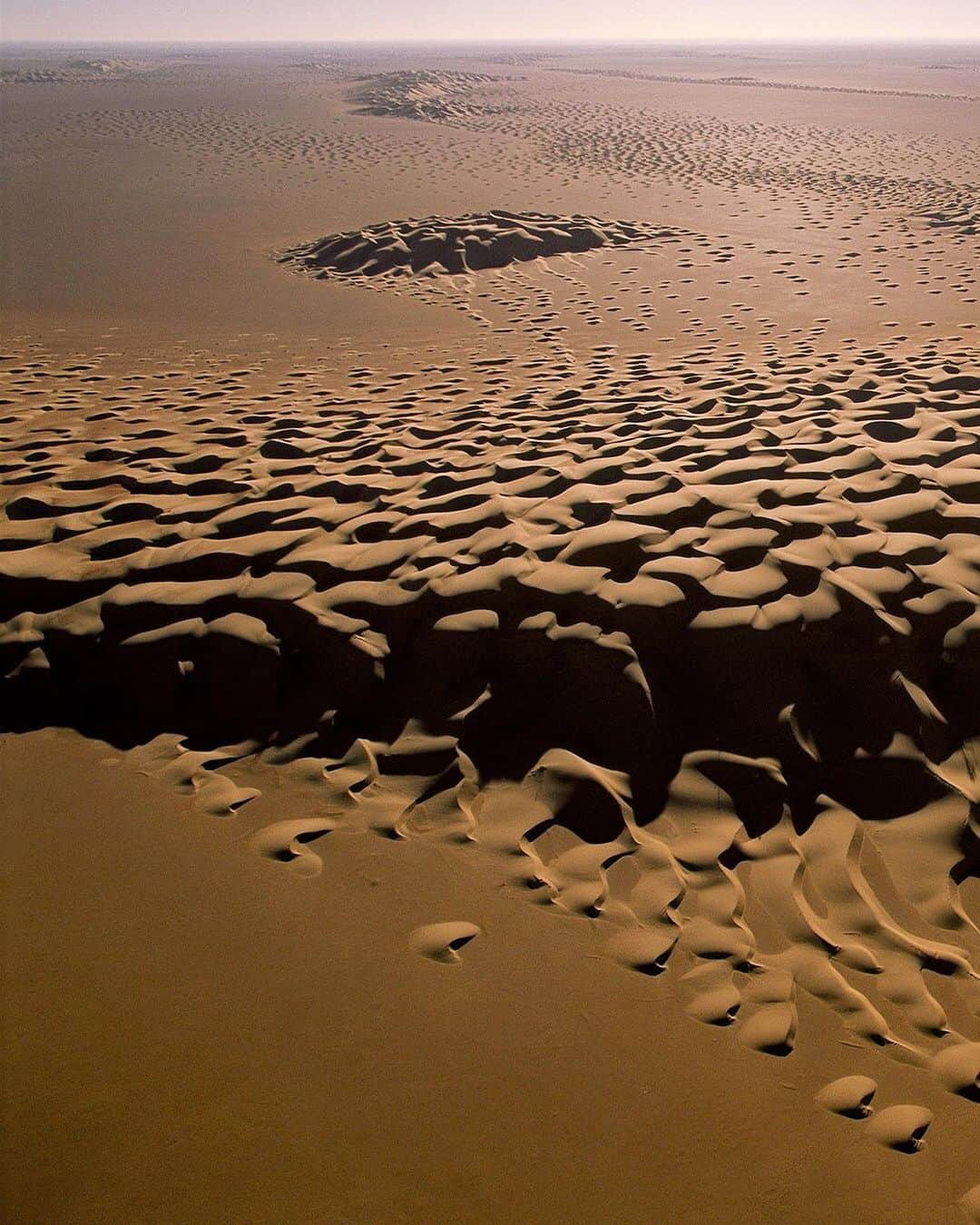 National Geographic Travelさんのインスタグラム写真 - (National Geographic TravelInstagram)「Photo by George Steinmetz @geosteinmetz | On my second crossing of Arabia’s Empty Quarter, I found some strange looking dunes in old satellite data that a friend of mine at NASA shared with me. It was pretty low resolution imagery, so I didn’t really know what to expect when I took off with my paraglider at sunrise. 90% of life is showing up! This monster barchan dune appeared to be spawning. #hyperarid #geomorphology #paramotor To explore more of our earth from above, follow @geosteinmetz.」8月1日 1時02分 - natgeotravel