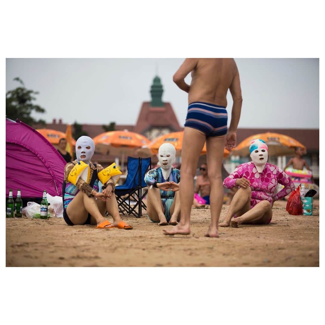 Magnum Photosさんのインスタグラム写真 - (Magnum PhotosInstagram)「"The basic idea on sun protection in China is that traditionally fair skin is sought after as 'beautiful'" - @chiyin_sim . Magnum nominee @chiyin_sim shares her work documenting Chinese holiday culture including  the 'facekini' - the practice of wearing a face mask made from the Lycra-like material that swimsuits are made from. . See more on magnumphotos.com today. Link in bio. . PHOTO: Chinese sunbathers and swimmers enjoy an afternoon of sun at one of several public beaches in Qingdao. Some were hiding under umbrellas while some women bathers were wearing masks made out of bathing suit material over their heads, to ward off the sun. Qingdao, China. 2012. . © @chiyin_sim/#MagnumPhotos . #SimChiYin #China #Qingdao」8月3日 4時01分 - magnumphotos