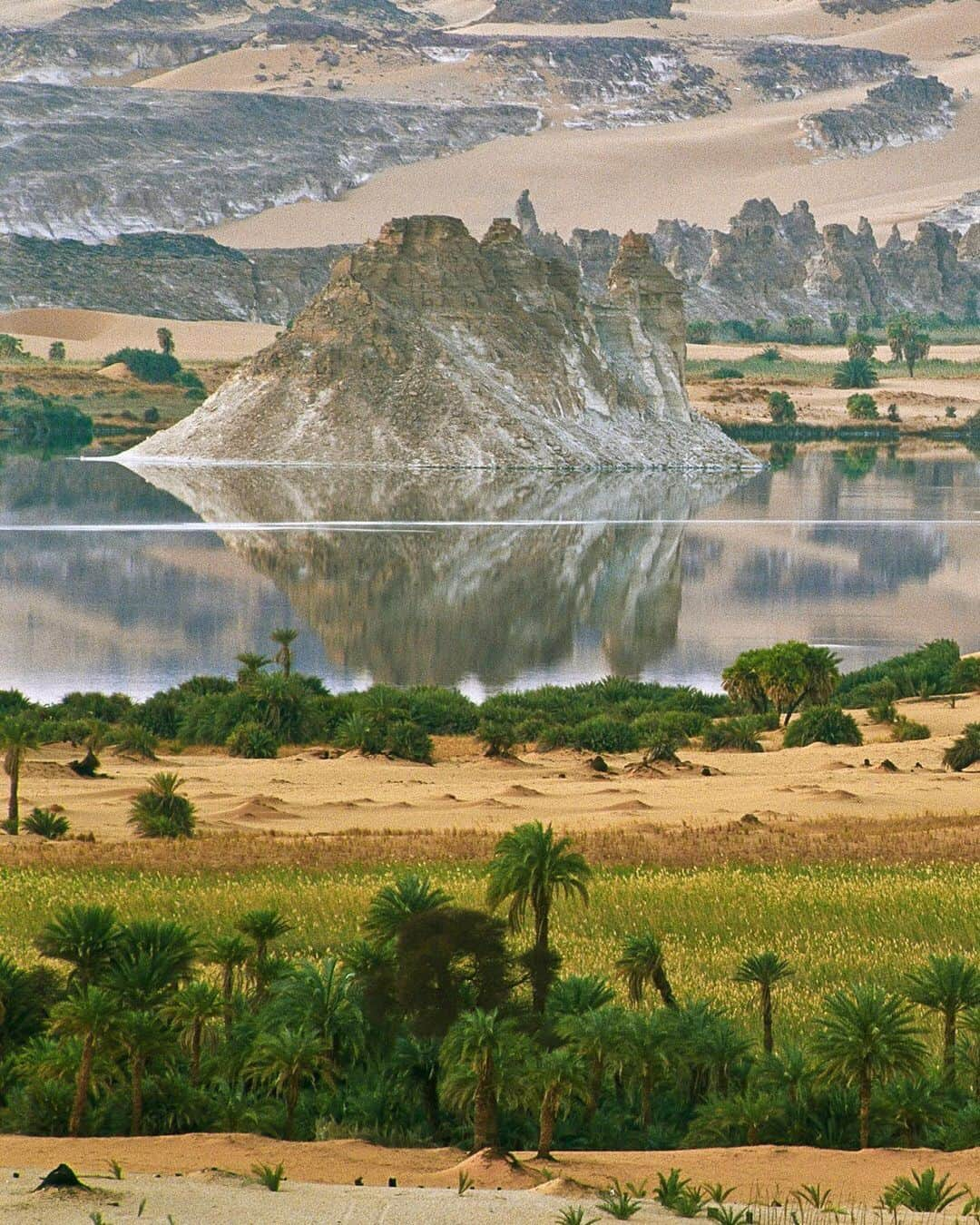 National Geographic Travelさんのインスタグラム写真 - (National Geographic TravelInstagram)「Photo by George Steinmetz @geosteinmetz | The miraculous oasis of Ounianga Serir in the Central Sahara of Chad is fed fresh water by an ancient aquifer from a time when the Sahara was a savannah. The lakes have slightly different elevations, and the higher ones are less salty. Maps from aerial surveys in 1954 show the lakes being larger and more connected, indicating that the water level has dropped. Seen here is the lowest lake, which is punctuated by ship-like islands of Nubian sandstone that were used as refuges by the local Tubu in times of attack. To explore more of our world, follow @geosteinmetz.」9月4日 1時05分 - natgeotravel