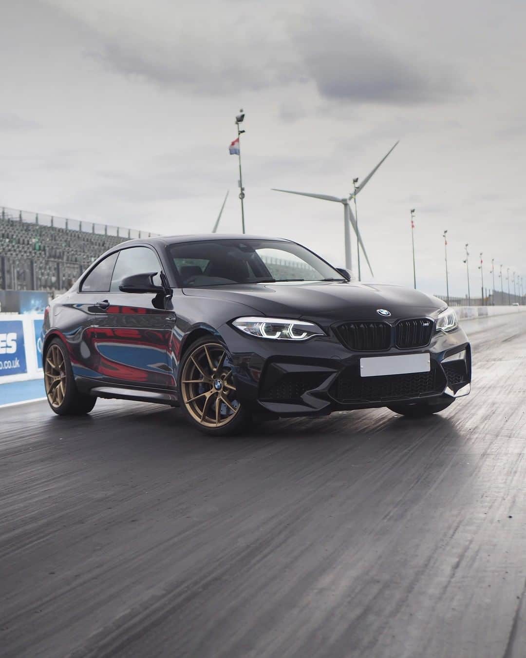 BMWのインスタグラム：「Engaged to the track, wearing a fantastic golden ring. The BMW M2 Competition. #TheM2 #BMW #M2 #BMWM #BMWrepost @black.m2c  __ BMW M2 Competition: Fuel consumption in l/100 km (combined): 10.0 (9.2). CO2 emissions in g/km (combined): 227 (209). The figures in brackets refer to the vehicle with seven-speed M double-clutch transmission with Drivelogic. The values of fuel consumptions, CO2 emissions and energy consumptions shown were determined according to the European Regulation (EC) 715/2007 in the version applicable at the time of type approval. The figures refer to a vehicle with basic configuration in Germany and the range shown considers optional equipment and the different size of wheels and tires available on the selected model. The values of the vehicles are already based on the new WLTP regulation and are translated back into NEDC-equivalent values in order to ensure the comparison between the vehicles. [With respect to these vehicles, for vehicle related taxes or other duties based (at least inter alia) on CO2-emissions the CO2 values may differ to the values stated here.] The CO2 efficiency specifications are determined according to Directive 1999/94/EC and the European Regulation in its current version applicable. The values shown are based on the fuel consumption, CO2 values and energy consumptions according to the NEDC cycle for the classification. For further information about the official fuel consumption and the specific CO2 emission of new passenger cars can be taken out of the „handbook of fuel consumption, the CO2 emission and power consumption of new passenger cars“, which is available at all selling points and at https://www.dat.de/angebote/verlagsprodukte/leitfaden-kraftstoffverbrauch.html.」