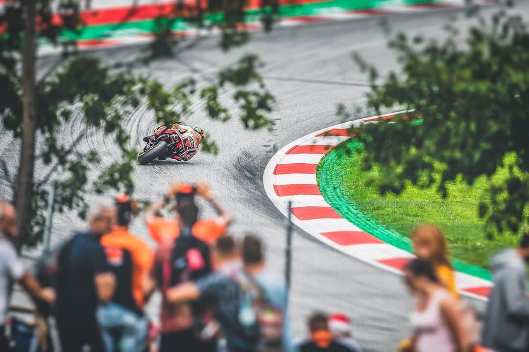 レプソル・ホンダのインスタグラム：「I've taken some of my favourite photos from spectator areas and with the variety of fantastic venues on the MotoGP calendar there are plenty of cool opportunities, including this one from the Red Bull Ring. I took this shot during the race on Sunday, there's a path that fans use to get to the back section of the track and it's a useful route to get from Turn 9 to Turn 4 in a short amount of time. As I was passing through I noticed a small opening where you can see the Austrian flag coloured kerbs framed nicely by the trees and fans. Stefan is blasting through the fast right hander before the last turn and putting on a show for the fans. • ISO 100,  400mm,  f/3.2,  1/1250sec」