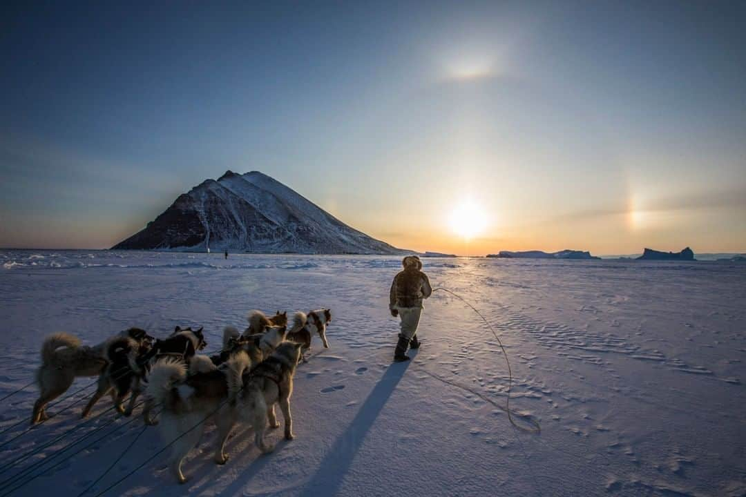 National Geographic Travelさんのインスタグラム写真 - (National Geographic TravelInstagram)「Photo by @paulnicklen | A hunter from Qaanaaq, Greenland walks cautiously across thin sea ice with his dog team; the man and his dogs and the surrounding land illuminated by beams of sunlight. The sun would not set again for months after the night this photo was taken, transforming this Arctic wonderland into a world of never-ending day. The rugged beauty of landscapes like these might be too stark and open for a lot of people. For me, trips to the Arctic are like going home. Follow me @paulnicklen for more stories from the field. #culture #greenland #sunset #arctic」8月16日 7時06分 - natgeotravel