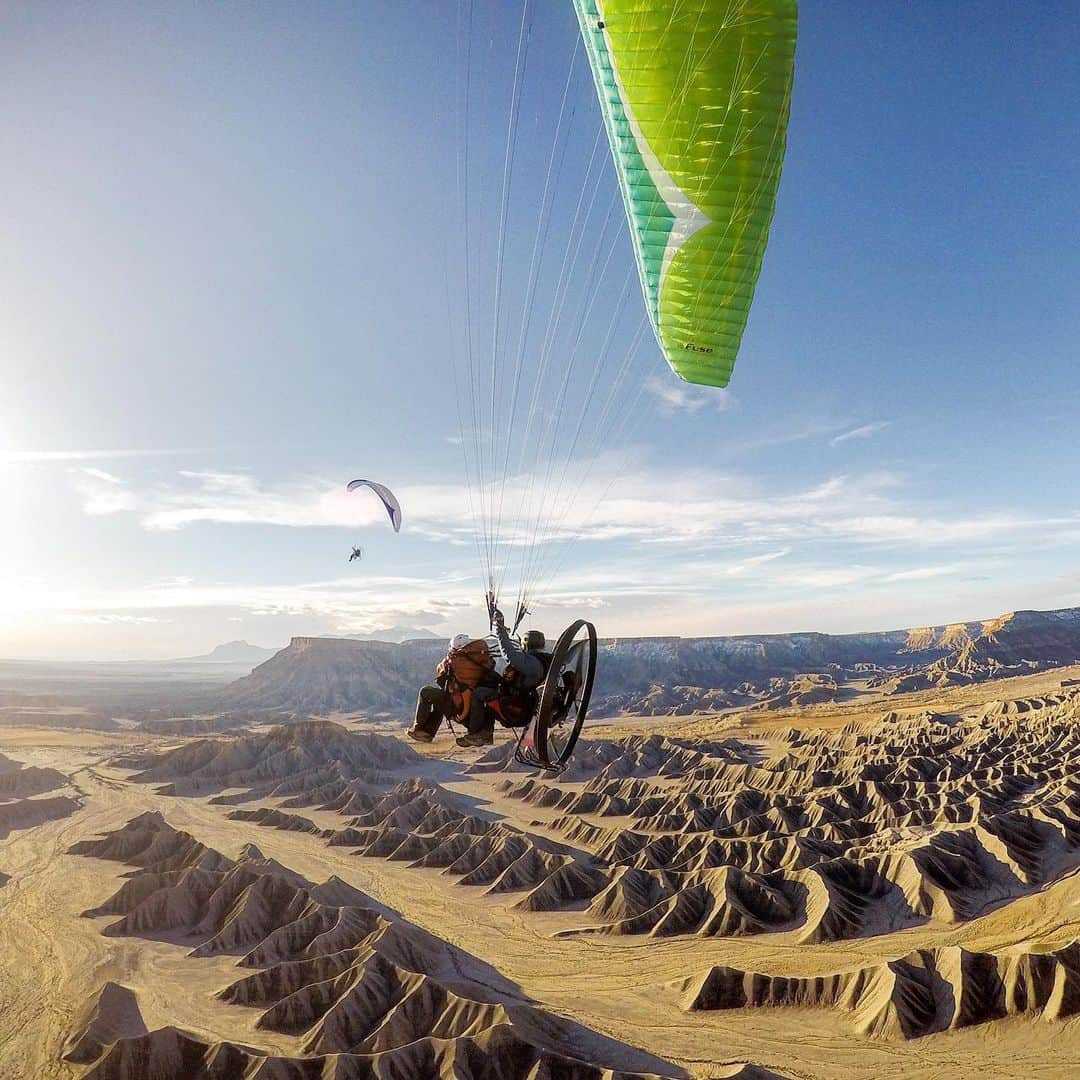 クリス・バーカードのインスタグラム：「Chasing unique angles is everything in photography. Although this one isn’t new by paragliding standards I was still pretty stoked on it when @shanedenherder showed me this small tag line & baby parachute he rigged up to hold my camera off his wing. It takes a perfect launch to not get tangled and obviously a time lapse setting to get it right. You hope that you get the tiny parachute vs camera weight just right to create enough lift. I love seeing this unique perspective of me shooting over the Utah desert.」