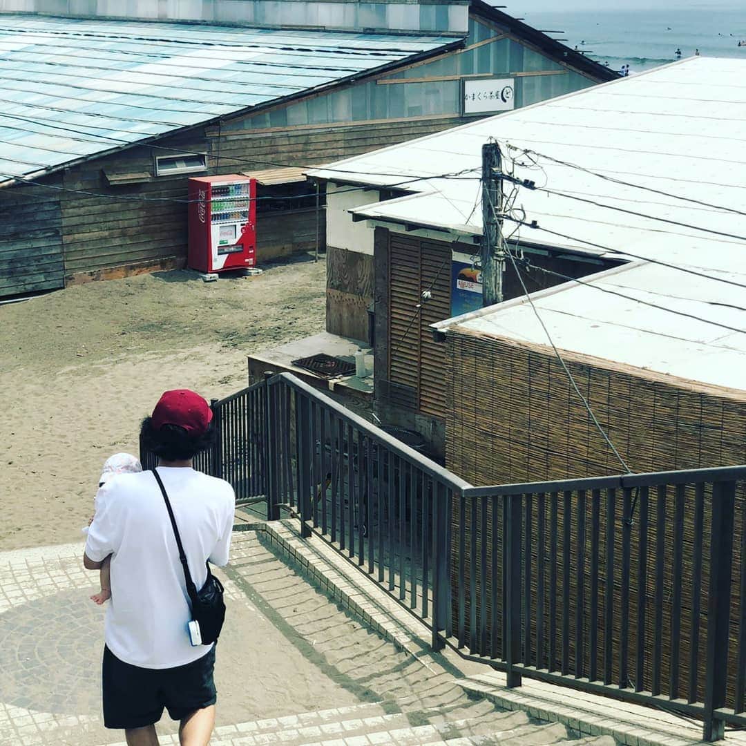 今井隆文のインスタグラム：「娘が6ヶ月になりまして、こりゃあめでたいということで、海を見せてあげたくて、鎌倉は由比が浜へ。  着くとすぐに、AMUSEの海の家を発見したが、ゴリゴリの兄ちゃんが店の前にいて、ちょっとな、、 と思い、そのまま海の前まで。  急に眠くなる娘。 アンモニア臭が漂う海。 そして、灼熱。  写真を撮れるだけ撮り、退散しようとすると、心優しき青年が写真撮りましょうか？と言ってくれて、めちゃくちゃ良い写真撮ってくれた！ これで、アンモニア臭は、チャラ！ ありがとうございました！  海の滞在時間10分！  鎌倉来たら、この看板が見たくなる！  半年ほんとにあっという間で、毎日幸せだ。」