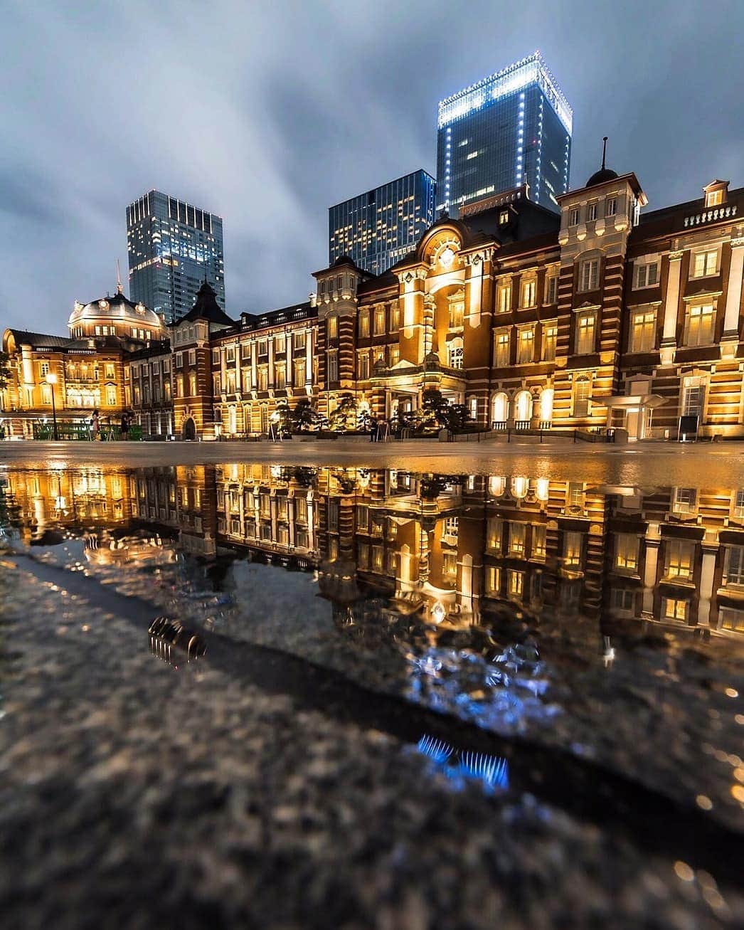 のインスタグラム：「雨上がり、水溜まりに映る東京駅。Tokyo Station reflecting off the water after the rain.  #雨上がり #水面鏡 #水鏡 #街の灯り #華やか #東京の街 #東京駅 #東京ステーション #丸の内駅前広場 #丸の内 #パレスホテル東京 #twinkle #aftertherain #magicalview #warmlights #waterreflection #mirroredreflection #poolofwater #TokyoStation #TokyoStationSquare #Marunouchi #PalaceHotelTokyo」