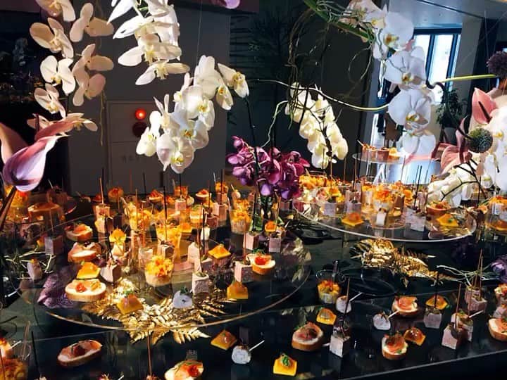 のインスタグラム：「.﻿ 🎵SOUND ON🎵﻿ 「IDEO TOKYO Office」1st Anniversary Party﻿ ﻿ ﻿ IDEO様のTOKYO Office1周年パーティーのテーマは「ALL THAT JAZZ」﻿ ﻿ バンドがJAZZを奏でる中、FOODやお酒を片手に、カジュアルにコミュニケーションを楽しむ大人のPARTYに合わせ、GOLD＆BLACKをベースカラーに、フィンガーフードのブッフェやフォトブース、ドリンクカウンターをつくらせていただきました。﻿ ﻿ ブッフェ台を回転させ、会場の雰囲気をぐっと華やかに演出✨﻿ ﻿ ﻿ 【MENU】﻿ ・鮭のテリーヌ 柚子と昆布のジュレ﻿ ・鶏肉のバロティーヌ 柑橘の香り﻿ ・パテ﻿ ・シーフードパエリア﻿ ・生ハム＆クリームチーズ＆セミドライトマトのオープンサンド﻿ ﻿ ﻿ ﻿ Art Direction by @0130nao and @wsomeya  Flower by﻿ @shigeru_abe_florist  Photo by @ayatoozawa ﻿ ﻿ follow us!﻿ @crazy_kitchen_insta」