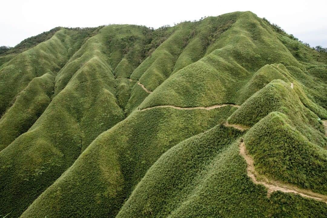 のインスタグラム：「🌏探検に出発！ワンダーランド・オブ・アジア🌏 チャイナ エアライン x 写真家小林賢伍がワンダーランド・オブ・アジア“台湾”にお連れします✈　http://bit.ly/2KONZuA  今日のご紹介： 聖母登山步道　こんなに大きなデザートを見たことのある人は...おそらくいないでしょう！ 聖母登山歩道は2つの区間から成ります。最初の区間は、五峰旗瀑布と通天橋を結ぶ産業道路です。通天橋を通過して登山歩道が始まると、豊かな自然に驚くことでしょう。森を抜けると雄大な五峰旗山が目の前に広がります。深緑色の木々に覆われた折り重なる尾根の姿は、遠目には抹茶のデザートのように見えます。途方もない自然の力によって形作られたこの景観には、思わず感動してしまいます。チャイナ エアラインに乗ってデザートのような山を見に行ってみませんか。  交通アクセス：バスまたは鉄道で礁渓駅まで行き、そこから台湾観光シャトルに乗り、五峰旗風景特定区で降ります。  チャイナ エアラインオリジナルグッズが当たる抽選キャンペーンも実施中です。ダイナスティ・フライヤー・プログラム会員にご登録(https://bit.ly/2HNe37Y)　いただければ、どなた様も応募可能です☝ふるってご応募ください🎁✨ おトクな運賃はこちら↓ https://bit.ly/2zppzCG  #チャイナエアライン #chinaairlines #中華航空 #天合聯盟 #スカイチーム　#SkyTeam #チャイナエアラインでどこ行きたい #台湾 #台湾旅行 #小林賢伍 #写真 #カメラ」