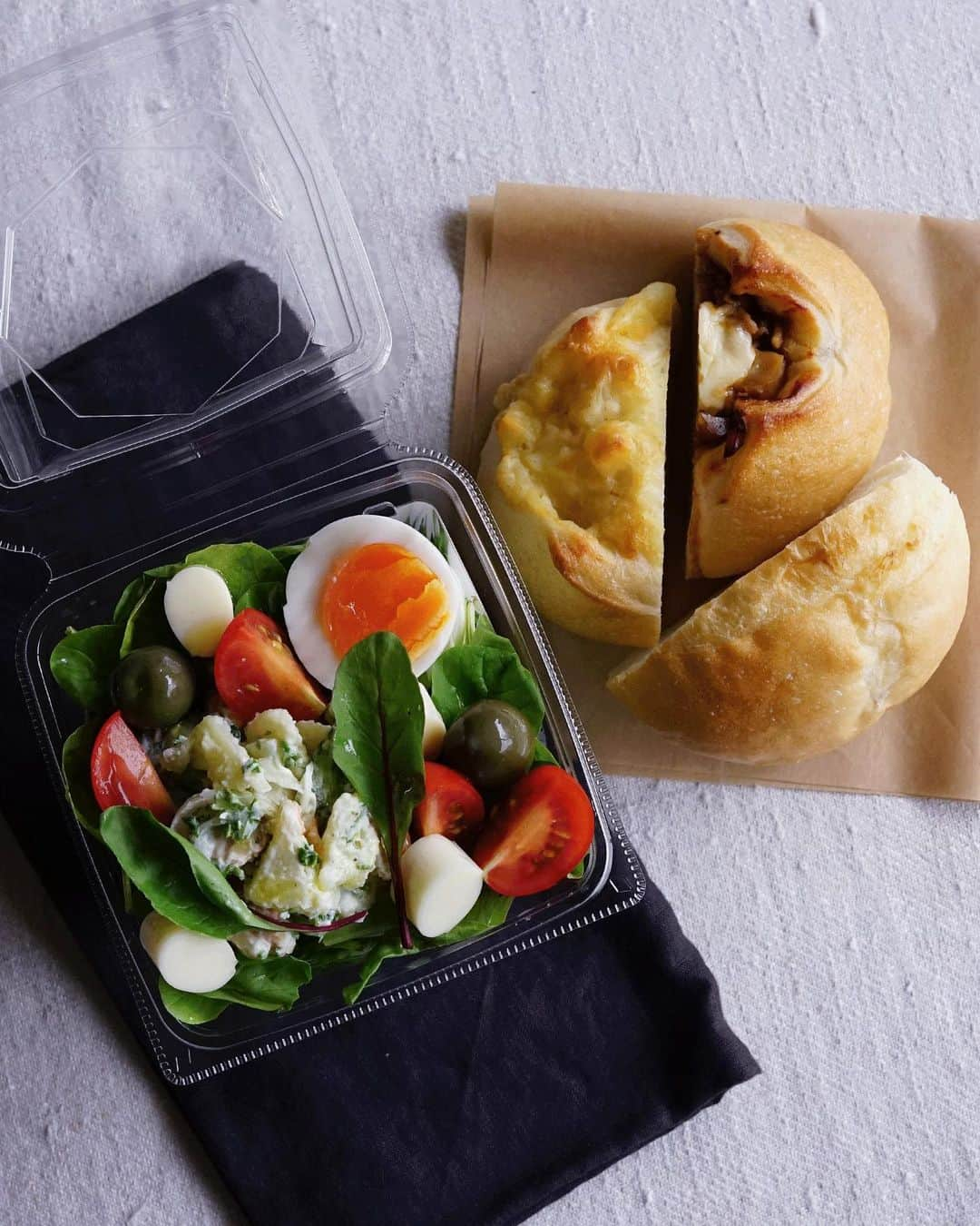 Ryoko Yunokiのインスタグラム：「+ + + Bread and salad bento/パンとサラダのお弁当 . *some bread *Green salad, topped with potato salad, baby tomatoes, cheese, hard-boiled egg and green olives, seasoned with salt/pepper and drizzled olive oil . *パン *グリーンサラダ。ポテトサラダ、プチトマト、チーズ、ゆで卵、グリーンオリーブ。味付けは塩胡椒とオリーブオイル。 + + + #bento #お弁当 #丸の内弁当 #f52grams #紙パック弁当」