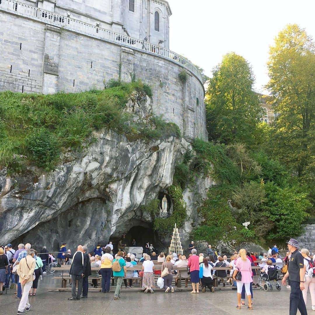 bon ponさんのインスタグラム写真 - (bon ponInstagram)「南フランス オクシタニー地方の旅🇫🇷 9月17日(火) 《ルルド Lourdes》 1858年2月11日、ポー川のほとりにある洞窟の近くに薪を集めに来た14歳の少女ベルナデット・スビルーの前に聖母マリアが現れました。合計で18回、聖母マリアはベルナデットの前に出現し、泉へ行って水を飲み、顔を洗いなさいと命じました。洞窟近くの地面を掘ると泉がわき始め、その湧き水によって病気が治癒する奇跡が何度も起きたといいます。ルルドは170か国から年間600万人が集まるカトリック最大の巡礼地となりました。 ＊ 旅の最終日に念願のルルドへ行くことができました。 フランス国内で、ルルドはパリに次いでホテルの数が多いそうです。それほど多くの巡礼者が訪れていることに驚きました。 聖域の外は、土産屋が立ち並びとても賑やかですが、聖域に入ると一転して厳かな雰囲気に満ちていました。 そこに自分達が立っていることに、言葉では表せない感動に包まれました🙏✨ ・ 【マッサビエルの洞窟】 聖母が出現したとされる洞窟。奇跡の泉はマリア像の左下奥にあり、今も泉がわいています。 ＊ 岩に触れ伝いながら、泉の湧くところへ進んで行きました。 ガラスに覆われて直に触ることはできませんが、洞窟の右手に泉の水を汲む場所がありました。ボタンを押すと水が出ます。この水は、顔を洗うことも飲むこともできます。 清きものとなれますように… ・ ロウソクを奉納して、聖堂へ。 ・ @Tourisme_en_Occitanie ・ ・ #TourismeOccitanie #DestinationPyrenees #Lourdes #フランス観光開発機構 #南フランス #オクシタニー地方 #ルルド　#夫婦 #60代 #ファッション #コーディネート #リンクコーデ #夫婦コーデ #グレイヘア #白髪 #共白髪 #couple #over60 #fashion #coordinate #instafashion #instagramjapan #greyhair #bonpon511 ・ つづく」9月23日 20時47分 - bonpon511