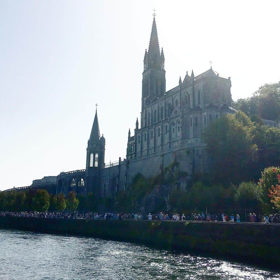 bon ponさんのインスタグラム写真 - (bon ponInstagram)「南フランス オクシタニー地方の旅🇫🇷 9月17日(火) 《ルルド Lourdes》 1858年2月11日、ポー川のほとりにある洞窟の近くに薪を集めに来た14歳の少女ベルナデット・スビルーの前に聖母マリアが現れました。合計で18回、聖母マリアはベルナデットの前に出現し、泉へ行って水を飲み、顔を洗いなさいと命じました。洞窟近くの地面を掘ると泉がわき始め、その湧き水によって病気が治癒する奇跡が何度も起きたといいます。ルルドは170か国から年間600万人が集まるカトリック最大の巡礼地となりました。 ＊ 旅の最終日に念願のルルドへ行くことができました。 フランス国内で、ルルドはパリに次いでホテルの数が多いそうです。それほど多くの巡礼者が訪れていることに驚きました。 聖域の外は、土産屋が立ち並びとても賑やかですが、聖域に入ると一転して厳かな雰囲気に満ちていました。 そこに自分達が立っていることに、言葉では表せない感動に包まれました🙏✨ ・ 【マッサビエルの洞窟】 聖母が出現したとされる洞窟。奇跡の泉はマリア像の左下奥にあり、今も泉がわいています。 ＊ 岩に触れ伝いながら、泉の湧くところへ進んで行きました。 ガラスに覆われて直に触ることはできませんが、洞窟の右手に泉の水を汲む場所がありました。ボタンを押すと水が出ます。この水は、顔を洗うことも飲むこともできます。 清きものとなれますように… ・ ロウソクを奉納して、聖堂へ。 ・ @Tourisme_en_Occitanie ・ ・ #TourismeOccitanie #DestinationPyrenees #Lourdes #フランス観光開発機構 #南フランス #オクシタニー地方 #ルルド　#夫婦 #60代 #ファッション #コーディネート #リンクコーデ #夫婦コーデ #グレイヘア #白髪 #共白髪 #couple #over60 #fashion #coordinate #instafashion #instagramjapan #greyhair #bonpon511 ・ つづく」9月23日 20時47分 - bonpon511