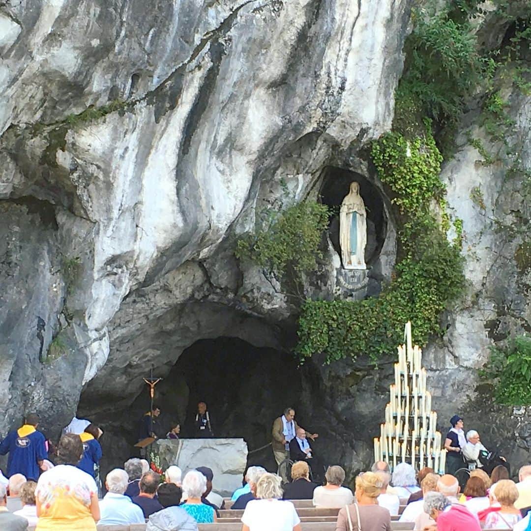 bon ponさんのインスタグラム写真 - (bon ponInstagram)「南フランス オクシタニー地方の旅🇫🇷 9月17日(火) 《ルルド Lourdes》 1858年2月11日、ポー川のほとりにある洞窟の近くに薪を集めに来た14歳の少女ベルナデット・スビルーの前に聖母マリアが現れました。合計で18回、聖母マリアはベルナデットの前に出現し、泉へ行って水を飲み、顔を洗いなさいと命じました。洞窟近くの地面を掘ると泉がわき始め、その湧き水によって病気が治癒する奇跡が何度も起きたといいます。ルルドは170か国から年間600万人が集まるカトリック最大の巡礼地となりました。 ＊ 旅の最終日に念願のルルドへ行くことができました。 フランス国内で、ルルドはパリに次いでホテルの数が多いそうです。それほど多くの巡礼者が訪れていることに驚きました。 聖域の外は、土産屋が立ち並びとても賑やかですが、聖域に入ると一転して厳かな雰囲気に満ちていました。 そこに自分達が立っていることに、言葉では表せない感動に包まれました🙏✨ ・ 【マッサビエルの洞窟】 聖母が出現したとされる洞窟。奇跡の泉はマリア像の左下奥にあり、今も泉がわいています。 ＊ 岩に触れ伝いながら、泉の湧くところへ進んで行きました。 ガラスに覆われて直に触ることはできませんが、洞窟の右手に泉の水を汲む場所がありました。ボタンを押すと水が出ます。この水は、顔を洗うことも飲むこともできます。 清きものとなれますように… ・ ロウソクを奉納して、聖堂へ。 ・ @Tourisme_en_Occitanie ・ ・ #TourismeOccitanie #DestinationPyrenees #Lourdes #フランス観光開発機構 #南フランス #オクシタニー地方 #ルルド　#夫婦 #60代 #ファッション #コーディネート #リンクコーデ #夫婦コーデ #グレイヘア #白髪 #共白髪 #couple #over60 #fashion #coordinate #instafashion #instagramjapan #greyhair #bonpon511 ・ つづく」9月23日 20時47分 - bonpon511