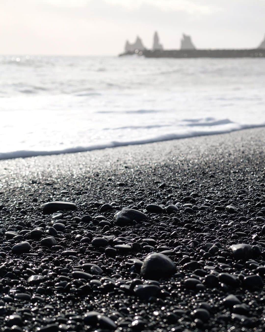 武智志穂さんのインスタグラム写真 - (武智志穂Instagram)「📍Reynisdrangar﻿ ﻿ 南アイスランドにある人口350人ほどの町・ヴィークのすぐ側にある、伝説でトロールが太陽の光を浴びて石になったとされるレイニスドランガル。（遠く奥に見えてる溶岩柱）﻿ ﻿ フィルターも加工も無しで、モノトーンの世界。﻿ ﻿ ブラックサンドビーチには、波にもまれて角が取れた石が沢山転がっていました。﻿ ﻿ ﻿ #志穂sTrip #Iceland #icelandtravel #火と氷の国 #レイニスドランガル」10月20日 10時35分 - shiho_takechi