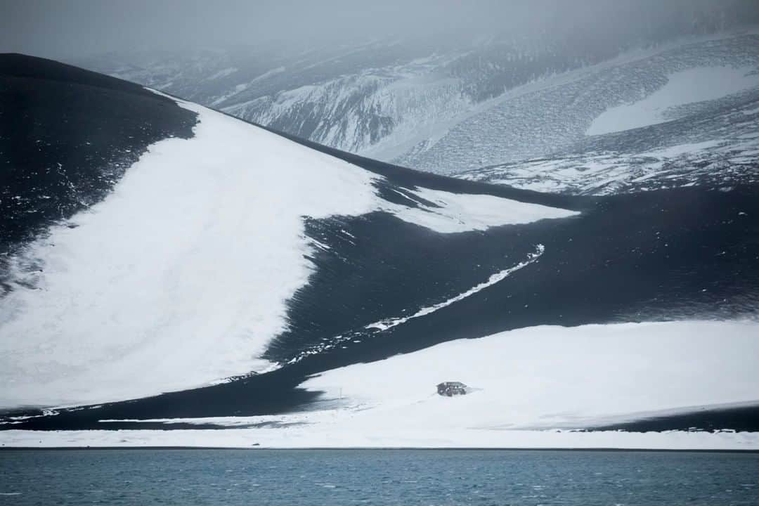 National Geographic Travelさんのインスタグラム写真 - (National Geographic TravelInstagram)「Photo by @acacia.johnson | On Deception Island, the remains of a research station's hut are dwarfed by a dramatic slope of snow and ash. This active volcanic caldera in Antarctica's South Shetland Islands is a popular destination for visitors by ship. They sail inside the caldera to witness the striking juxtaposition of glaciers, volcanic activity, and colonies of penguins. #antarctica #deceptionisland #southshetlandislands」10月11日 1時06分 - natgeotravel