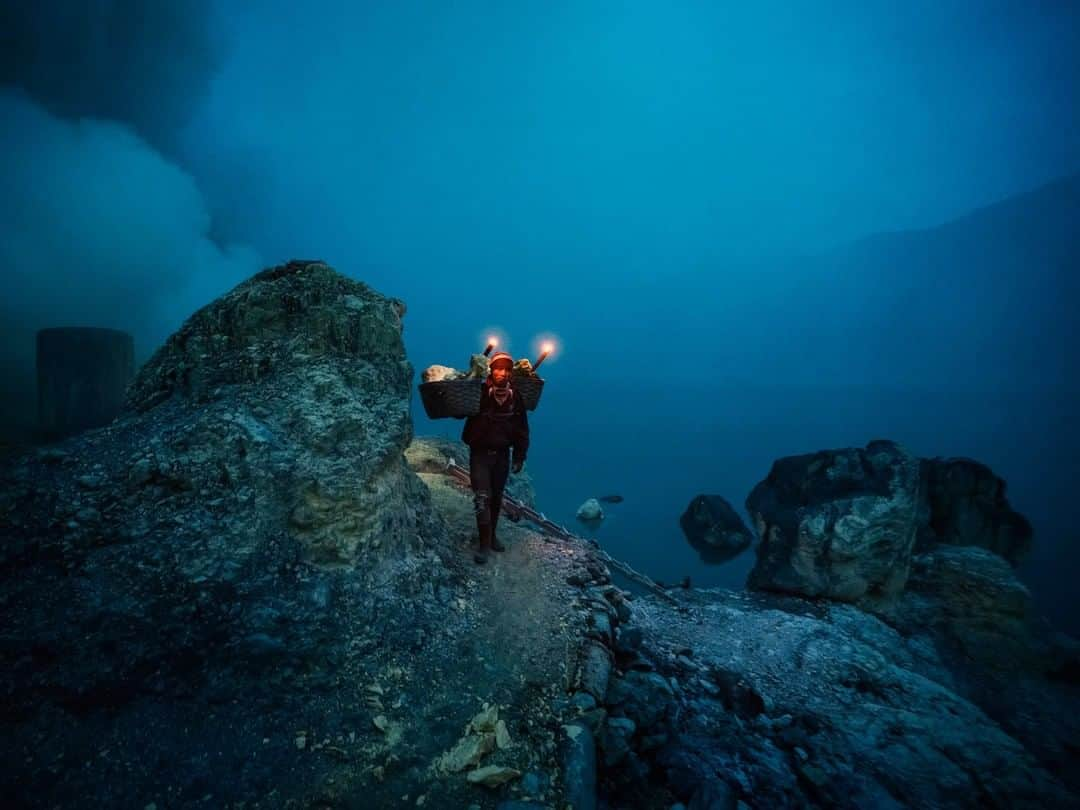 National Geographic Travelさんのインスタグラム写真 - (National Geographic TravelInstagram)「Photo by @andrea_frazzetta | Mount Ijen, on the island of Java, Indonesia, hosts one of the last remaining active sulfur mines in the world. While its otherworldly vistas have captivated scientists and travelers for more than two centuries, in recent decades the miners themselves have become a controversial tourist attraction. Hadis, portrayed in this picture, is 36 years old and has been a full-time miner for 10 years. Every day miners make the arduous trek up Ijen’s 9,000-foot slopes under the cover darkness before descending another 3,000 feet into the crater. Enveloped in toxic fumes and heat, they chip away at the hardened blocks and carry loads up to 200 pounds back up the crater twice a day. Follow @andrea_frazzetta to learn more about this story. #ijen #java #indonesia」10月11日 9時04分 - natgeotravel