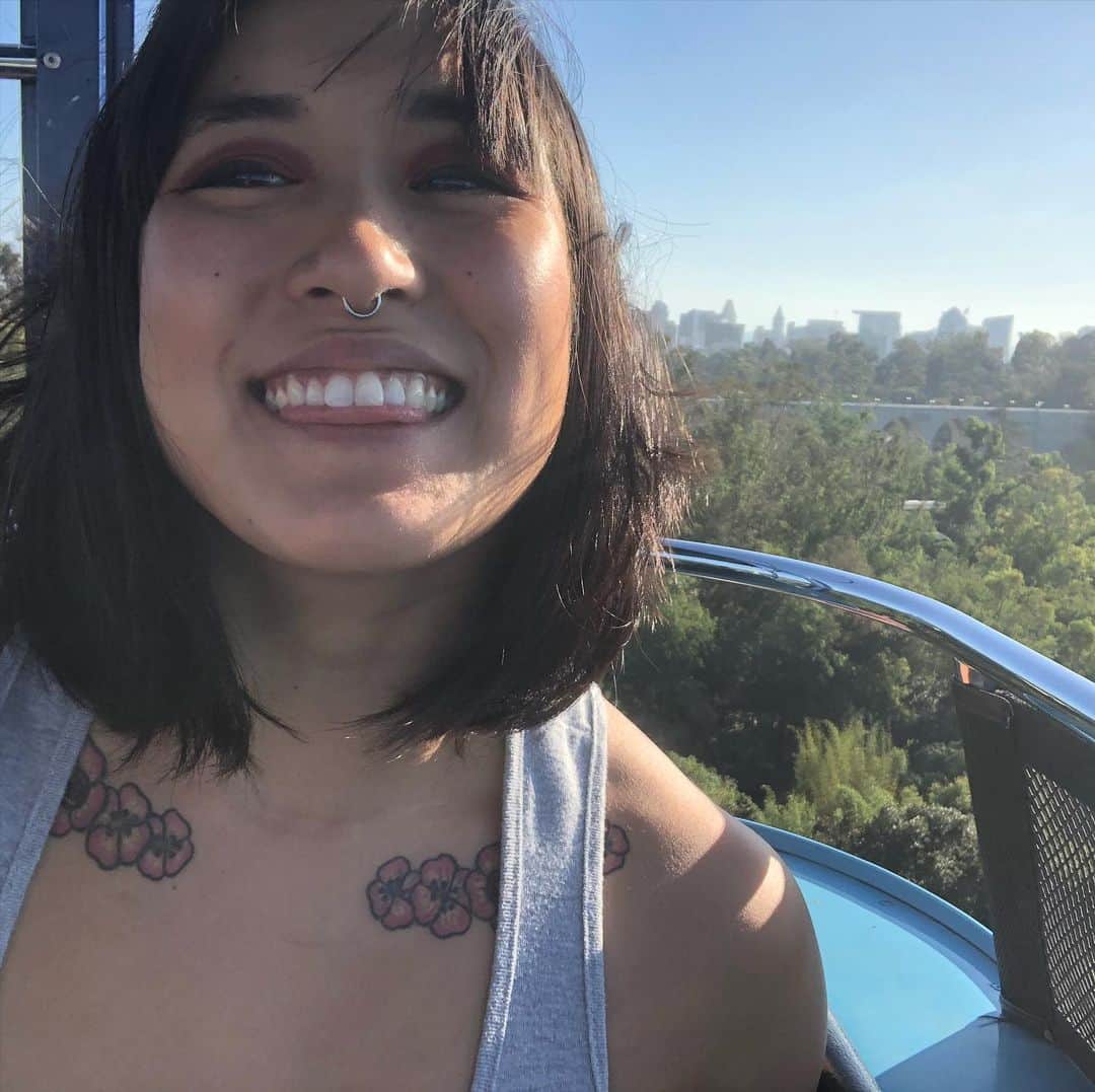 のインスタグラム：「TBH I have been grappling with how to use this platform since having my IG deleted twice. It makes it hard to share my parts of me on here for fear that at any point this account could be taken down. So to challenge that here is a quick selfie and a happy moment from a friend adventure with the sweet @the_harmony_lee. [image description: Mia smiling like a happy goober while riding the aerial tram at San Diego zoo with zoo greenery and San Diego in the background.]」