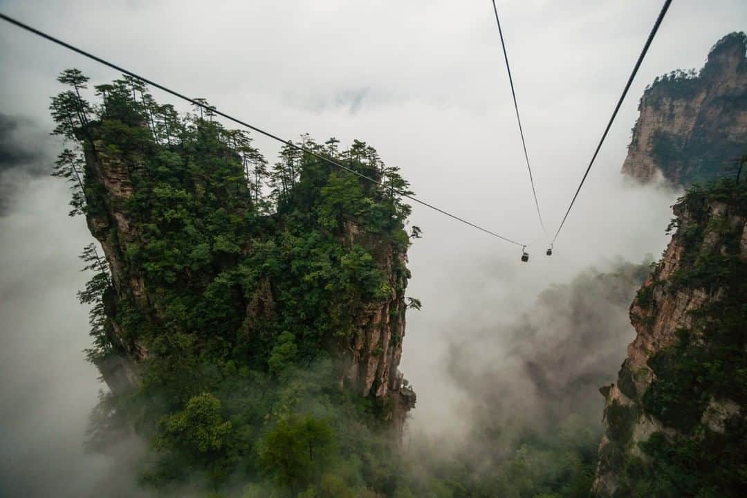 National Geographic Travelさんのインスタグラム写真 - (National Geographic TravelInstagram)「Photo by Michael Yamashita @yamashitaphoto | Fog covers this view from the top of the Tianzi Mountain Range in Zhangjiajie National Forest Park, China. The tiny cable cars give you a sense of how immense these sandstone towers are. #zhangjiajie #wulingyuan #tianzimountain #china」10月15日 5時05分 - natgeotravel