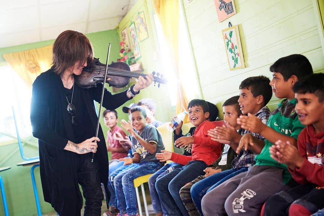 SUGIZOさんのインスタグラム写真 - (SUGIZOInstagram)「３年ぶり、２回目となるヨルダンのザアタリ難民キャンプ。 今回はKnK (国境なき子どもたち) がプログラムを実施している、キャンプ内のヨルダン公立学校にて、その教室でババガヌージュとしてワークショップ的な演奏を行ってきた。 ムスリム圏では完全に男子と女子のクラスが別れているけれど、両者とも本当に元気！ みんな故郷を追われ難民という立場を強いられてはいるけれど、その子供達の目には光と希望が見える。 ヴァイオリンを初めて見た子がほとんどで、その好奇心が爆発、最高に微笑ましかった。 みんなが大人になる頃には故郷シリアに帰れていますように・・・。 子供達が武器よりも楽器を手に取ってくれるような社会になりますように・・・。 Photo by Keiko TANABE.」10月16日 19時41分 - sugizo_official