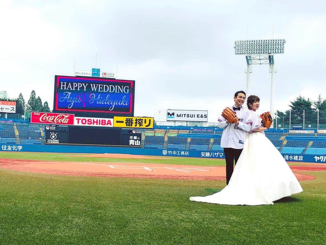 野崎鮎のインスタグラム：「神宮球場で夫婦でウェディングフォトのモデルをさせていただきました😍 これはユニフォーム＆グローブ着用バージョン⚾️ （ヤクルトスワローズファンだからヤクルトのユニだよね！） ウェディングドレスバージョンも もちろんあります♡ 野球ファン、ヤクルトスワローズファンにはたまらないロケーション撮影♡ 家族写真、友達や大切な人との記念写真も期間限定で募集しています📷💖 お問い合わせは 「明治記念館写真室」まで☎️ 大好きな場所で大好きな人達と幸せで笑顔溢れる素敵な写真を沢山撮っていただいたので、 少しずつアップしていきます♡ 旦那様、親友、家族とも撮っていただきました😭 本当に嬉しくて楽しくて大切な瞬間を写真にして最高に幸せな思い出♡ 私の些細な一言で夢を叶えてくれる最高の旦那様でとっても幸せ♡ ありがとう♡  #ウェディング #ウェディングフォト #記念日 #思い出 #明治記念館 #明治神宮野球場 #神宮球場 #wedding #marriage #モデル #東京ヤクルトスワローズ #ヤクルトスワローズ #swallows #ユニフォーム #dress #weddingdress #dressblack #記念写真 #weddingphotography  #thankyou #iloveyou ♡ #happy #photooftheday」