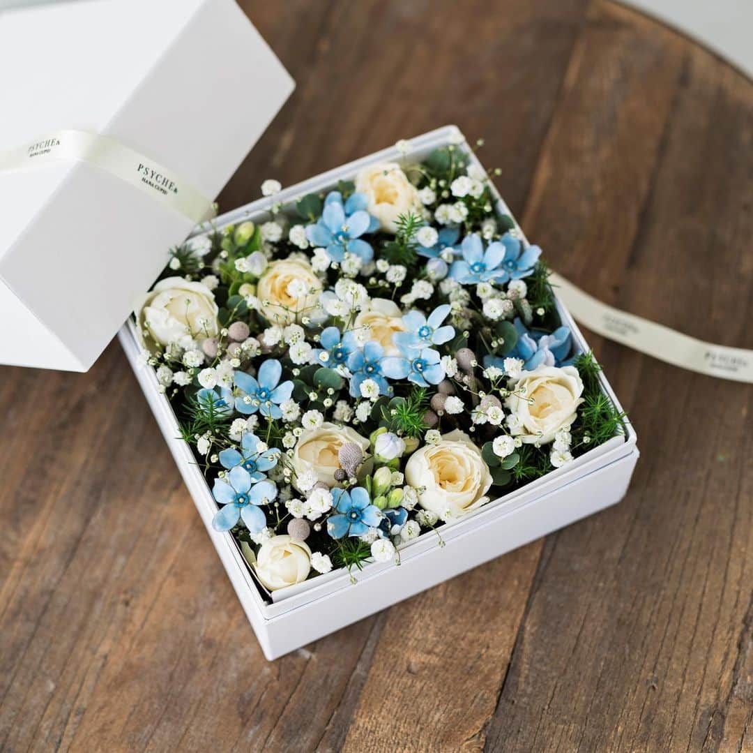 プシュケ[PSYCHE&]・花キューピットのインスタグラム：「. 冬の結婚祝いのテーマはサムシングブルー リボンをほどきそっとボックスをあけると、そこには思わず息をのむ美しい花々が広がっています。 優しい水色と白を基調としたフラワーボックスは、まるでお花畑に雪が舞っているよう。 幻想的なフラワーギフトで、大切な方にときめきをお届けします。 ｰｰｰｰｰｰｰｰｰｰｰｰｰｰｰｰｰｰｰｰｰｰｰｰｰｰｰｰｰｰｰｰｰｰｰｰｰｰｰｰｰｰｰｰｰｰｰｰｰｰｰ #プシュケ #花キューピット #花 #💐 #ザ花部 #サムシングブルー #ブルースター #カスミソウ #白バラ #冬 #冬の花 #クリスマス #winter #花束 #花に心を込めて #暮らしに花を #花のある暮らし #丁寧な暮らし #フラワーデザイン #インテリアフラワー #フラワーギフト #フラワーボックス #👰 #wedding #ウエディング  #プシュケ_Natural」
