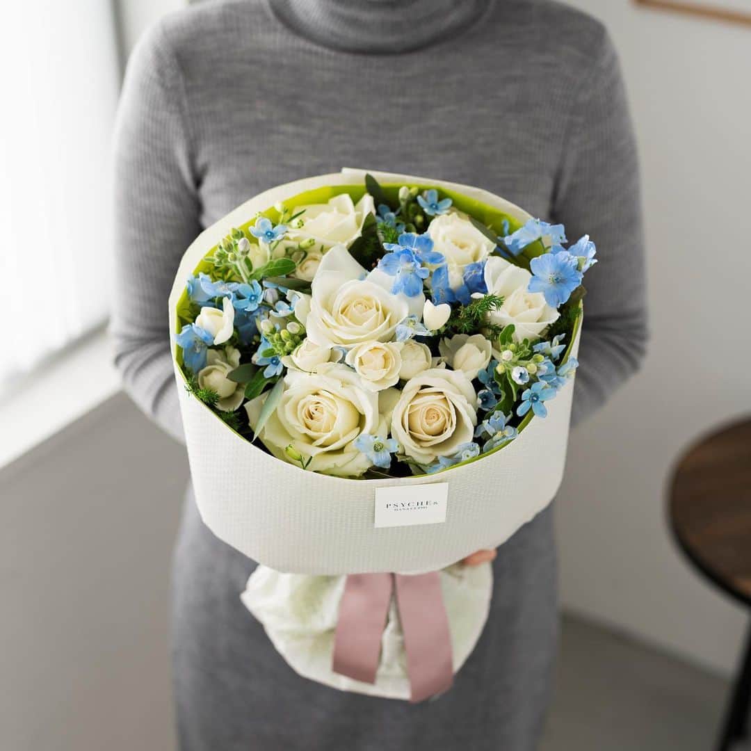 のインスタグラム：「. 冬の青空のように清々しい季節限定のブーケ。 「純潔」の花言葉にふさわしい白バラをたっぷり束ねて、特別な日を心からお祝いします。 サムシングブルーのブルースターやデルフィニウムがきらきらと光に反射し、ブーケの透明感を引き立てます。 2人にとって大切な日だからこそ、腕いっぱいの花を贈りませんか？ ｰｰｰｰｰｰｰｰｰｰｰｰｰｰｰｰｰｰｰｰｰｰｰｰｰｰｰｰｰｰｰｰｰｰｰｰｰｰｰｰｰｰｰｰｰｰｰｰｰｰｰ #プシュケ #花キューピット #花 #💐 #ザ花部 #サムシングブルー #ブルースター #デルフィニウム #カスミソウ #白バラ #冬 #冬の花 #クリスマス #winter #花束 #花に心を込めて #暮らしに花を #花のある暮らし #丁寧な暮らし #フラワーデザイン #インテリアフラワー #フラワーギフト #フラワーボックス #👰 #wedding #ウエディング  #結婚祝い #プシュケ_Natural」