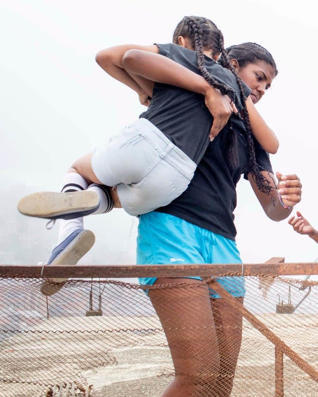 のインスタグラム：「Photo by Natalie Keyssar @nataliekeyssar | Two members of Moni Dance, a Caracas-based neighborhood dance team, hop a fence on a rooftop in the Catia area after performing at the opening of a new basketball court—part of a violence prevention initiative. Cultural programs like Moni Dance have become all the more important amid Venezuela's ongoing crisis, where grassroots arts collectives create a space for normalcy and empowerment.」