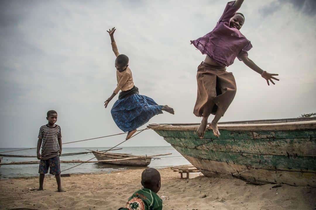 のインスタグラム：「Photo by Ami Vitale @amivitale | Children from the village of Katumbi play and collect water near Lake Tanganyika, on the western edge of Tanzania. In 2011 and 2016, I went here with @nature_africa to photograph the Tuungane Project, which aims to create healthier families, fisheries, and forests. Here, only 1 in 10 girls finish secondary school, due to pregnancies, the time spent getting to school, or other challenges. But staying in school means these girls typically marry and start having children at a later age, and education provides women more opportunities to become employed, earn an income, and reduce their overall reliance on natural resources. In early 2019, @nature_africa donors built a life-changing, 80-bed girls’ dormitory next to Lagosa Secondary School. Girls who otherwise had no time to study due to long walks to school or faced other hardships at home now have a safe place to live and learn. Learn more by following @amivitale @nature_africa @thephotosociety and @nature_org #girls #letgirlslearn #tanzania #africa」