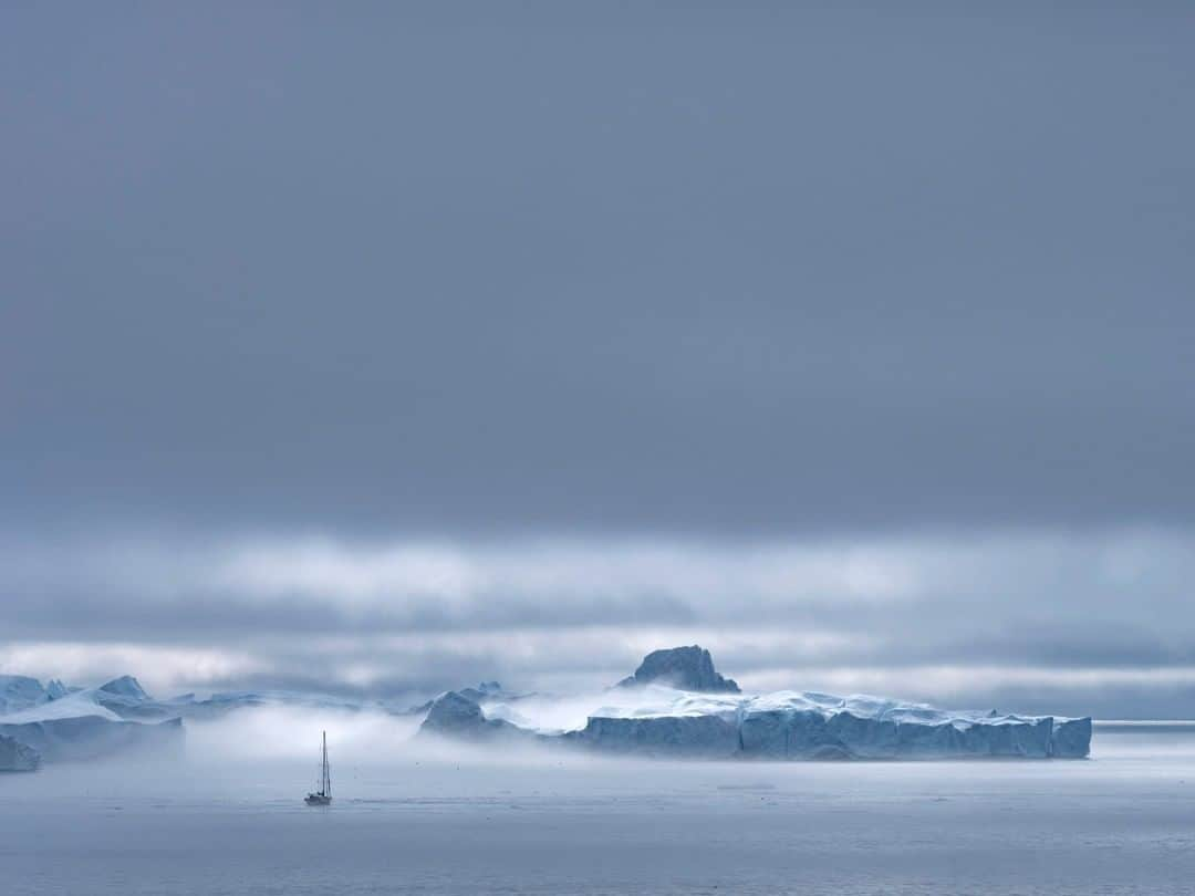 ナショナルジオグラフィックさんのインスタグラム写真 - (ナショナルジオグラフィックInstagram)「Photo by Stephen Wilkes @stephenwilkes |  A lone sailboat glides through the fog on a turbulent day in Greenland. Long-term residents of Greenland are seeing firsthand the impacts of climate change, from a decrease in dogsledding, shorter ice-fishing seasons, and increased deaths from falling through thinning ice. The weather across the country, which used to be steady and predictable, is becoming increasingly volatile and threatening a way of life. To see more photos from my travels near and far, follow me @stephenwilkes. #StephenWilkes #Greenland #Iceberg #Melting #Climatechange」11月11日 19時38分 - natgeo