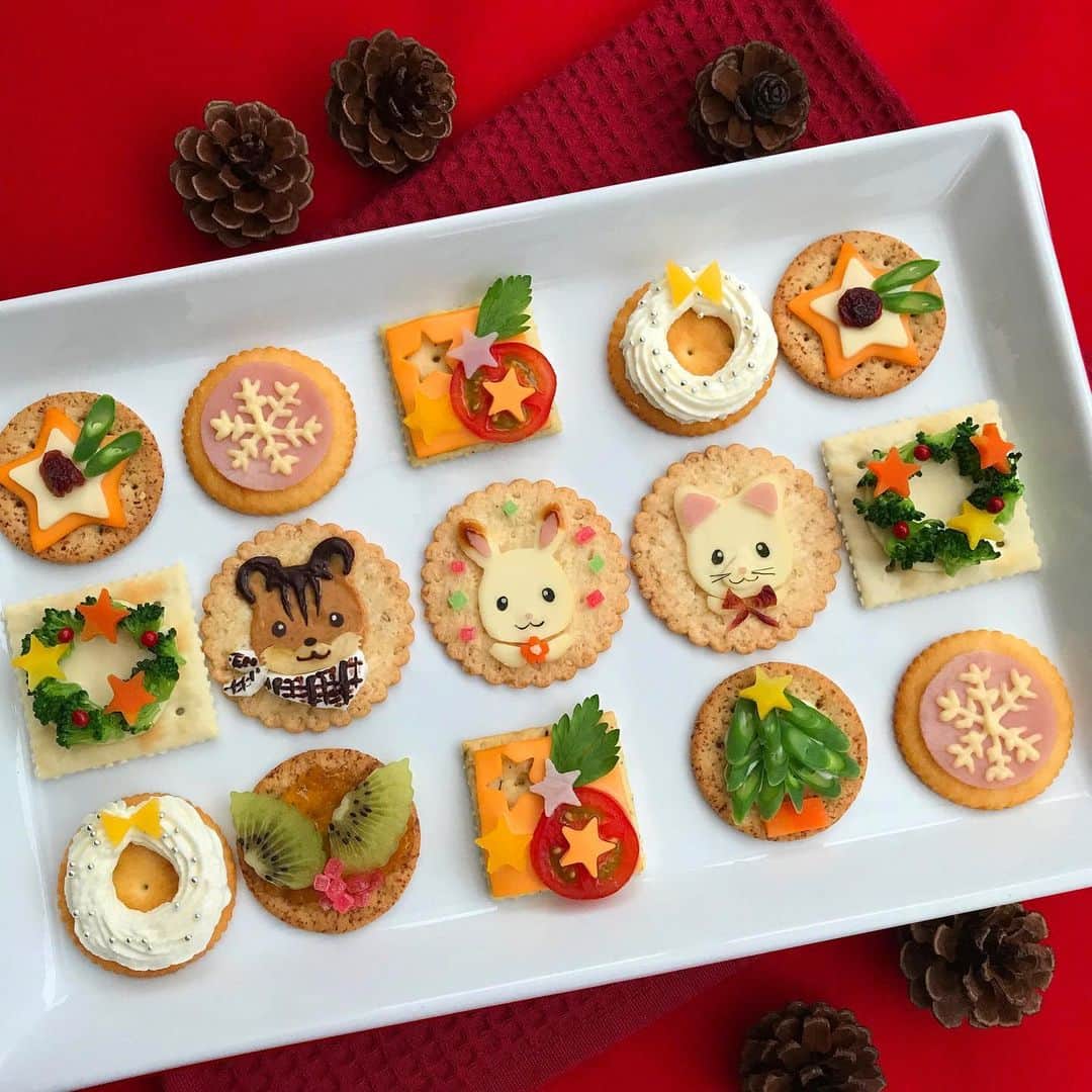 シルバニアファミリー【公式】 さんのインスタグラム写真 - (シルバニアファミリー【公式】 Instagram)「今年のクリスマスは、ショコラウサギちゃんたちのクリスマスカナッペを作ってみませんか？ とっても華やかで楽しい食卓になりますよ！ * -レシピ- 【ショコラウサギちゃん】 ・スライスチーズ(顔型に切ったもの・襟・目の光・花の中心)：適量 ・ハム(耳の部分・鼻)：2枚・1枚 ・ソース：少々 ・海苔(目・口)：少々 ・人参(茹でて花型に切る)：1個 ・ゼリーの飾り：適量 ＜作り方＞ クラッカーに輪郭を取ったスライスチーズをのせる。襟も作る。 耳にソースをのせ、耳と鼻の部分にハムをのせる。 海苔で目と口をつくり、チーズを小さく切り目に光を入れる。 お花型の人参をのせ、中心にチーズをのせる。 まわりにゼリーの飾りをのせる。 * 【くるみリスくん】 ・ピーナッツバター：適量 ・バナナ(口のまわり)：1個 ・チョコペン：適量 ・マシュマロ(襟の部分)：適量 <作り方> ピーナッツバターで輪郭をとる。 口のまわりをバナナで形どりのせ、溶かしたチョコペンで顔の模様を描き、目、鼻、口を描く。 マシュマロでスカーフを作りのせ、チョコペンでチェック模様を描く。 目の光をマシュマロで作り置く。 * 【シルクネコちゃん】 ・スライスチーズ(顔型に切ったもの・襟・目の光・口のまわり)：適量 ・ハム(耳の部分・鼻)：2枚・1枚 ・海苔(目・口・ヒゲ)：適量 ・ドライクランベリー(リボン状)：1セット <作り方> クラッカーに輪郭をとったスライスチーズをのせる。 襟、口のまわりの部分も切ってのせる。 耳と鼻にハムを切ってのせる。 海苔を切り、目、口、ひげをのせる。 リボンの部分はクランベリーを切ってのせる。 * #シルバニアファミリー #シルバニア #sylvanianfamilies #calicocritters #sylvanian #ドールハウス #dollhouse #ミニチュア #miniature #クリスマス #christmas #カナッペ #レシピ  #シルバニアファミリーてづくり部 #キャラフード #キャラごはん」12月9日 18時02分 - sylvanianfamilies_jp