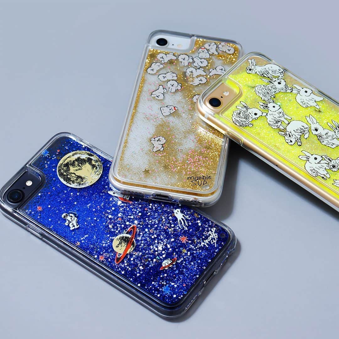 marbleSUD(マーブルシュッド) のインスタグラム：「春の新作iPhoneケースが一足早く登場。今回はmarble SUD初のグリッターケース。キラキラと輝きを放ちながらグリッターが動く様に、ギュッと心を鷲掴みにされてしまう可愛さです。  宇宙柄とウサギ柄はグリッターが、ビションフリーゼ柄はグリッターと一緒に小さなビションフリーゼもフワフワと浮遊します。動いている様子はストーリー&ハイライトで配信中！  その他、機種を選ばないマルチ対応のケースやあの便利アイテム同時発売！合わせてチェックしてくださいね！  online shop先行で本日より発売！直営店は13日(金)からの販売となります。」