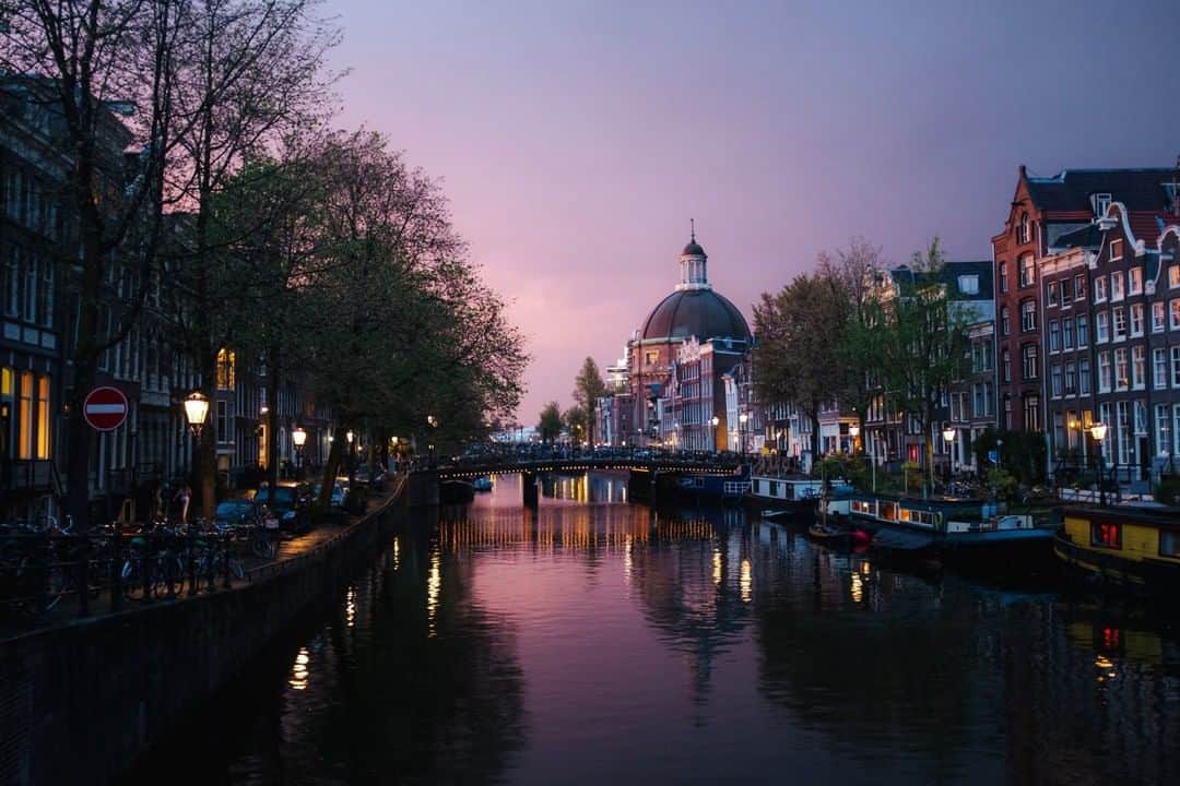 National Geographic Travelさんのインスタグラム写真 - (National Geographic TravelInstagram)「Photo by @MichaelGeorge | My first and only time in Amsterdam was to attend my best friend’s wedding. I arrived a day before everyone else and had a particularly sick feeling of jet lag. It was pouring rain, so I ended up sleeping most of the day away, occasionally looking out the window and watching people scramble around the canals. Just before sunset I couldn’t ignore my hunger any longer and took a long walk. I was so lucky I did. Not only did I instantly discover what a gorgeous city I was in, but the sky began putting on a show. There were golden clouds and rainbows against a distant, dark sky and the city came alive. Eventually the sunset faded to this gorgeous pinkish purple, a color I’ve rarely seen in my life. #amsterdam #sunset #purplesky #travel」11月19日 18時09分 - natgeotravel